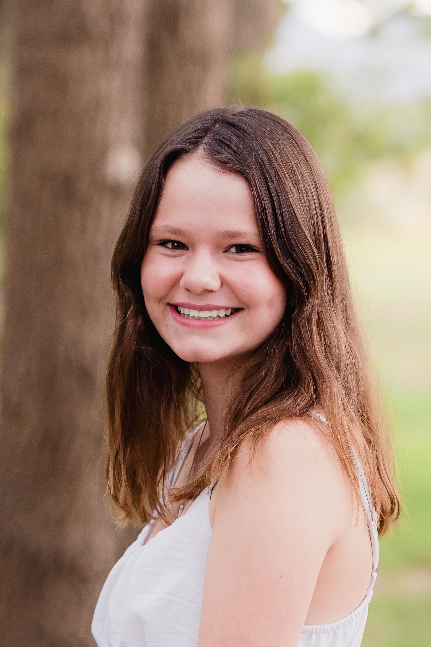 Teen girl, smiling, wearing white dress.