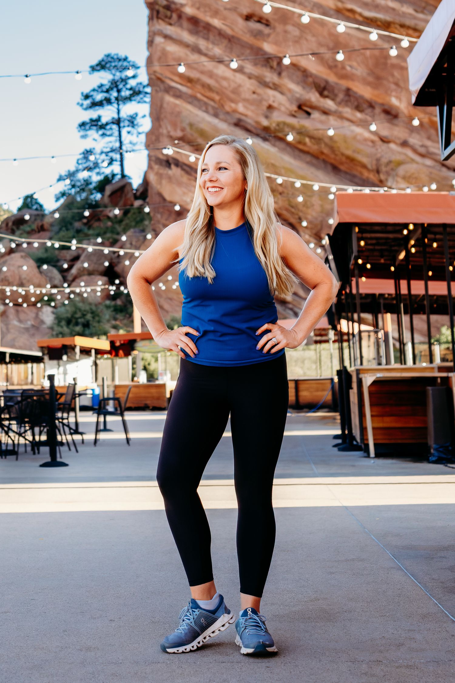 Fitness branding photography with female trainer standing in power pose at top of Red Rocks Amphitheater.