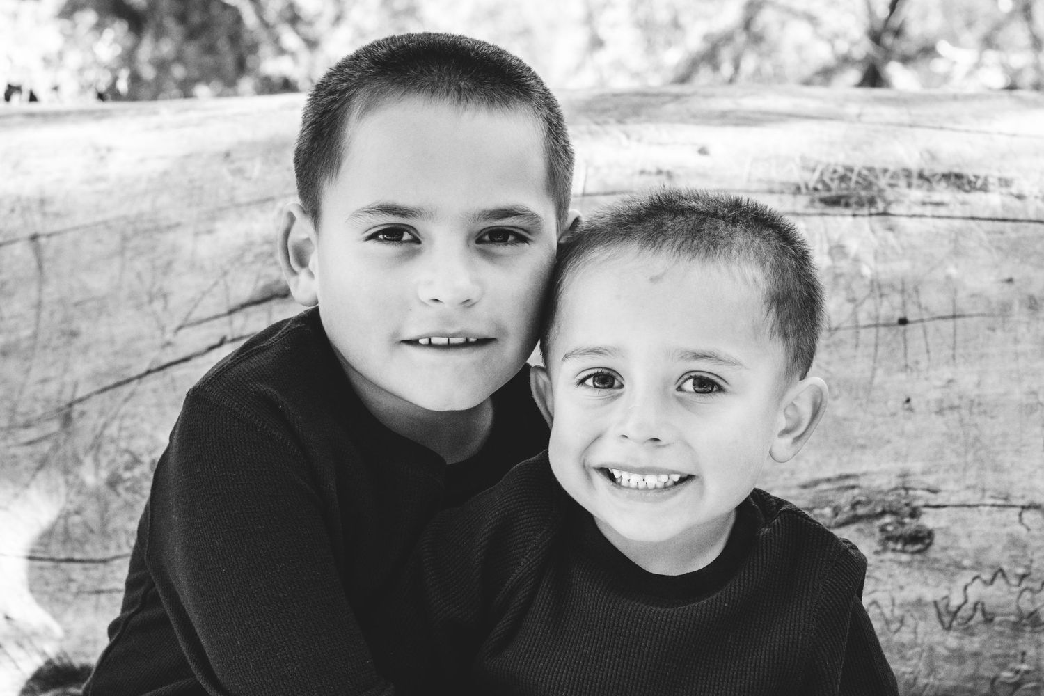 Black and white portrait of two young brothers, close together, smiling warmly.