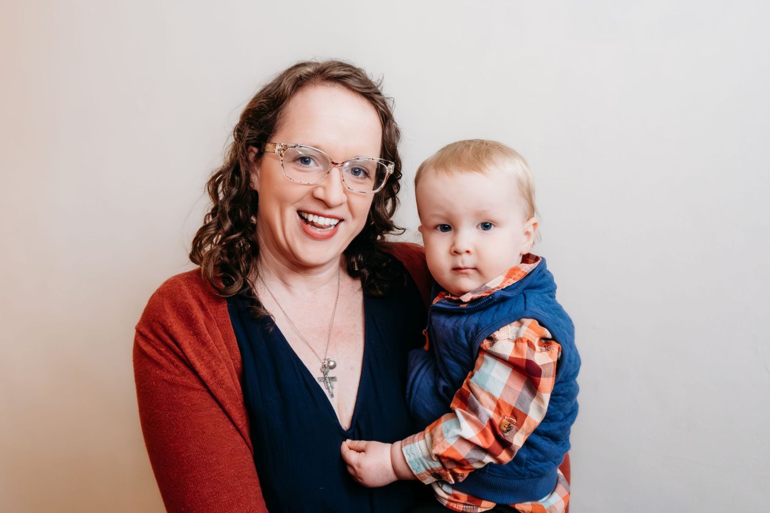 Studio portrait of mother holding toddler son, both smiling.