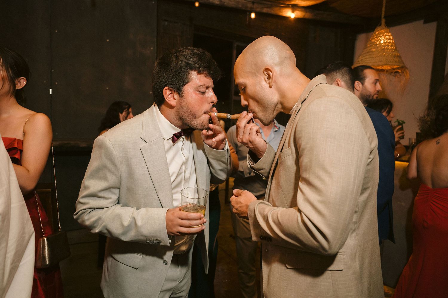 Party guests raise glasses to toast at a dimly lit indoor celebration.