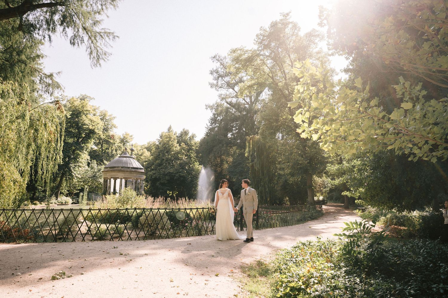 Golden sunlight illuminates romantic garden scene with ornate fence and natural landscaping.