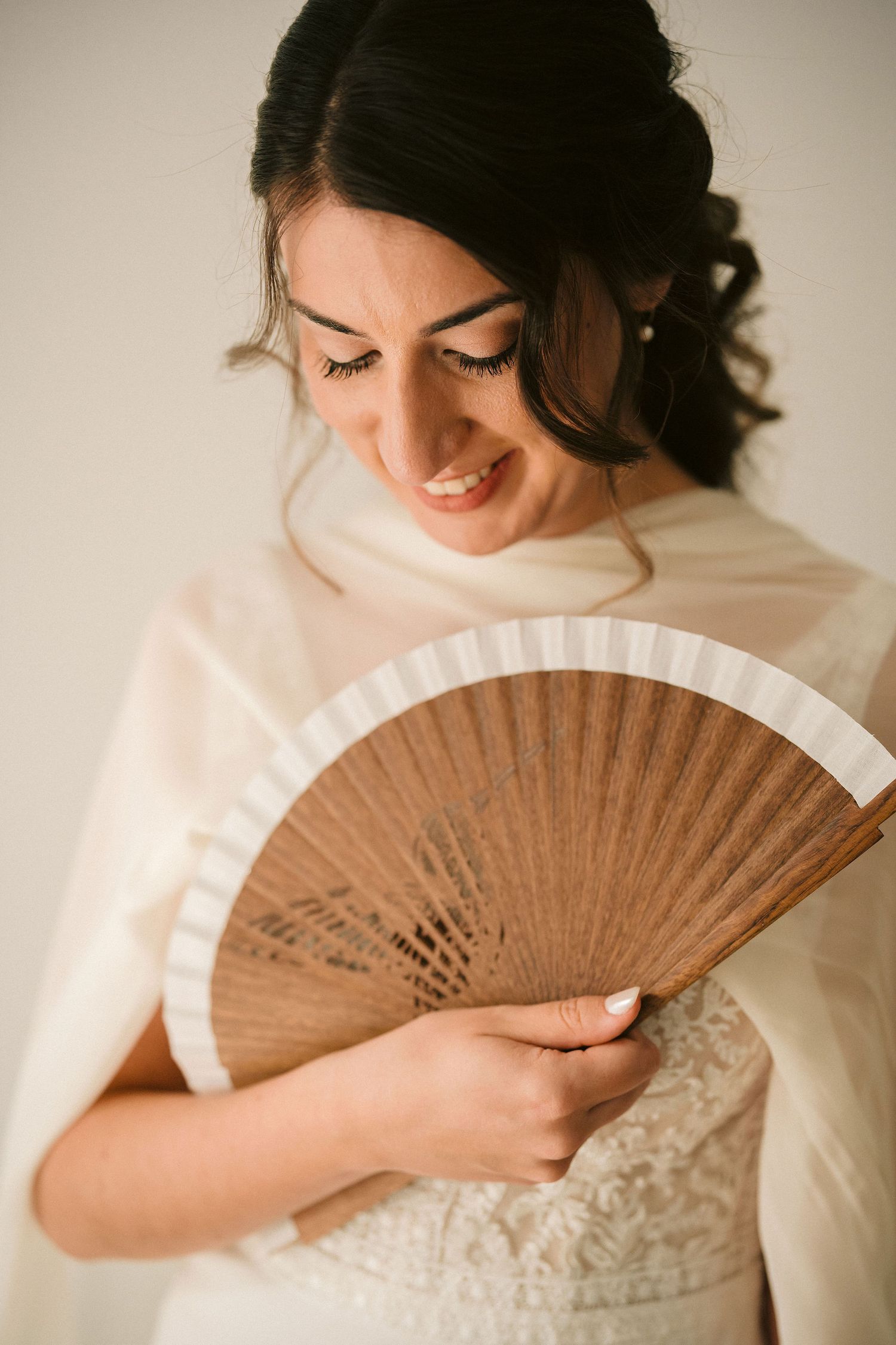 Four intimate close-up shots show someone in white clothing demurely posing with a vintage wooden hand fan against a neutral background.
