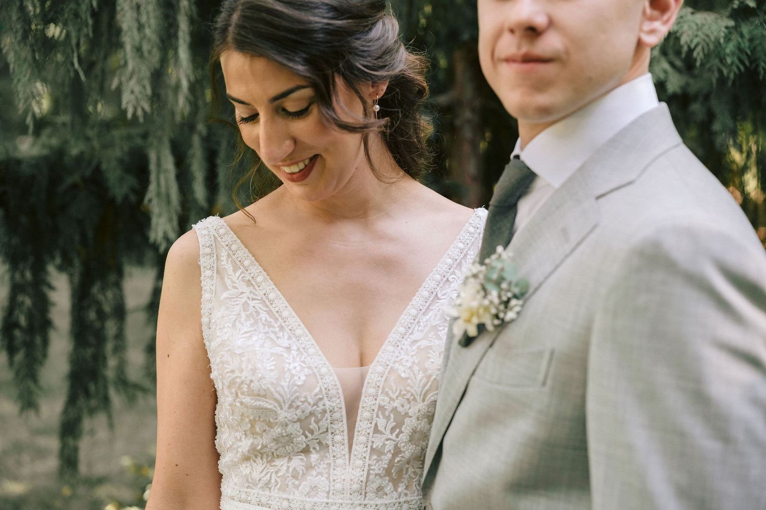 A couple in wedding attire share an intimate moment together in a lush outdoor garden setting.