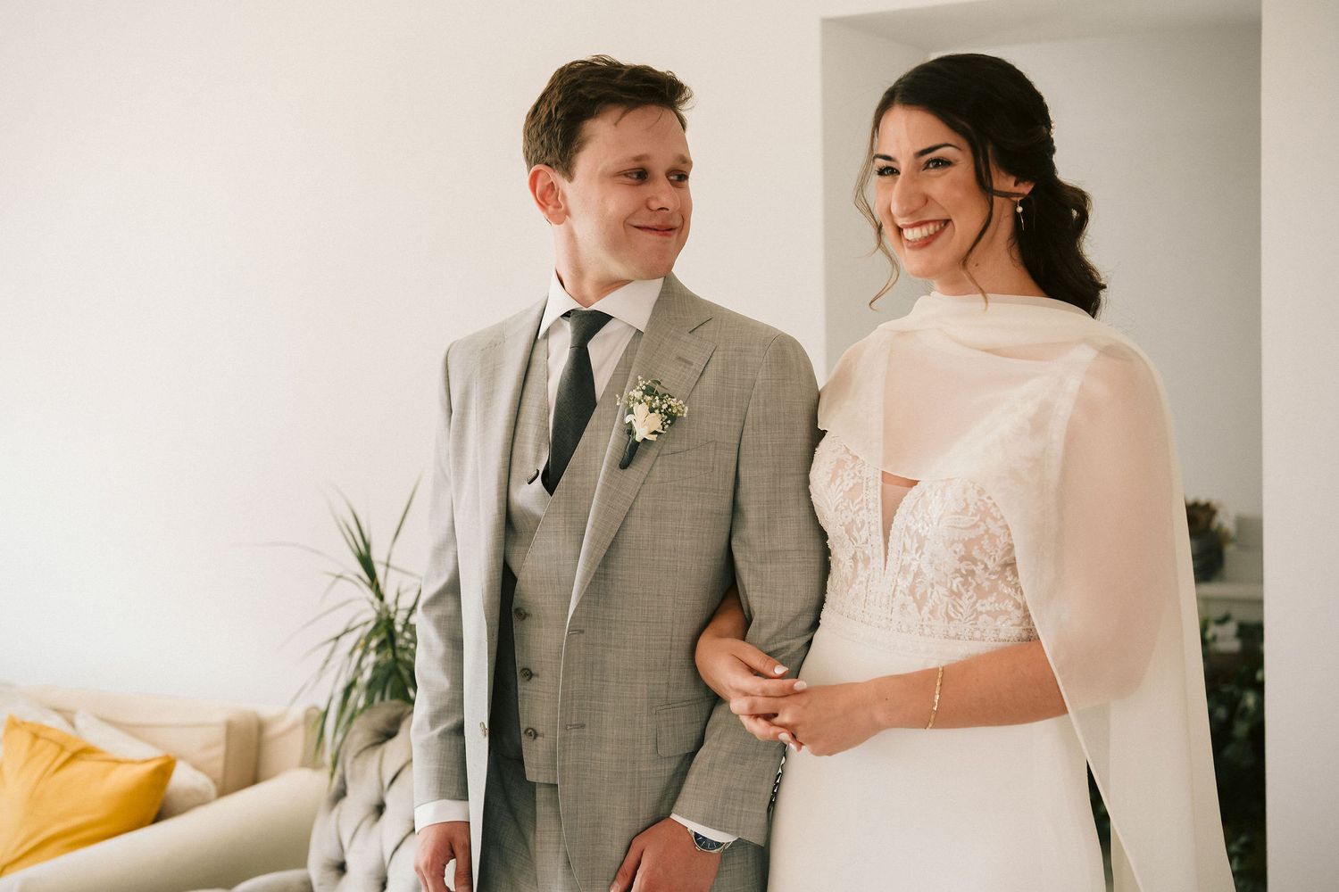 A couple shares a joyful moment together on their wedding day, with the bride in white and groom in a gray suit.