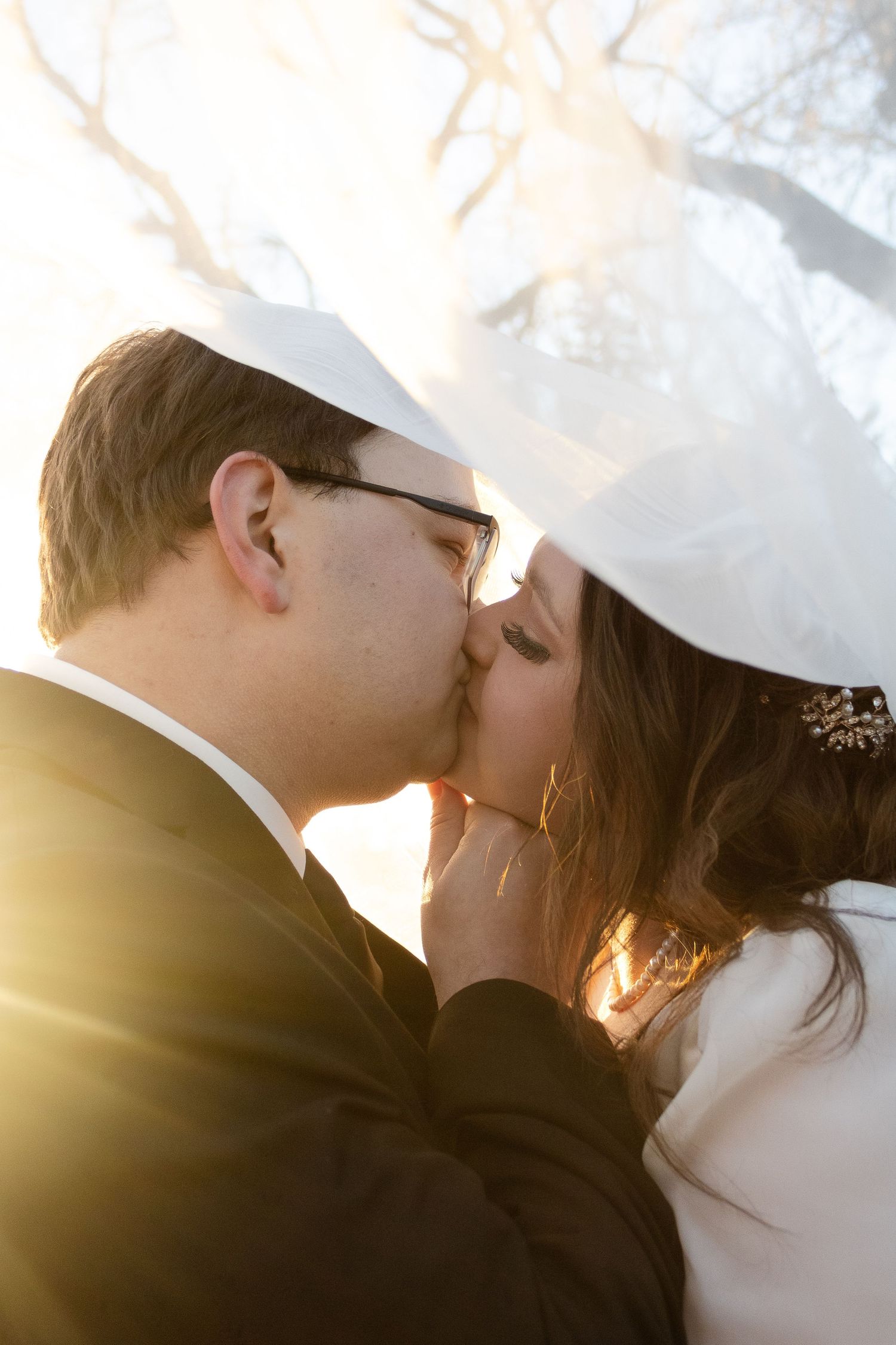 A romantic sunset wedding photo shows an intimate moment backlit by golden sunlight.