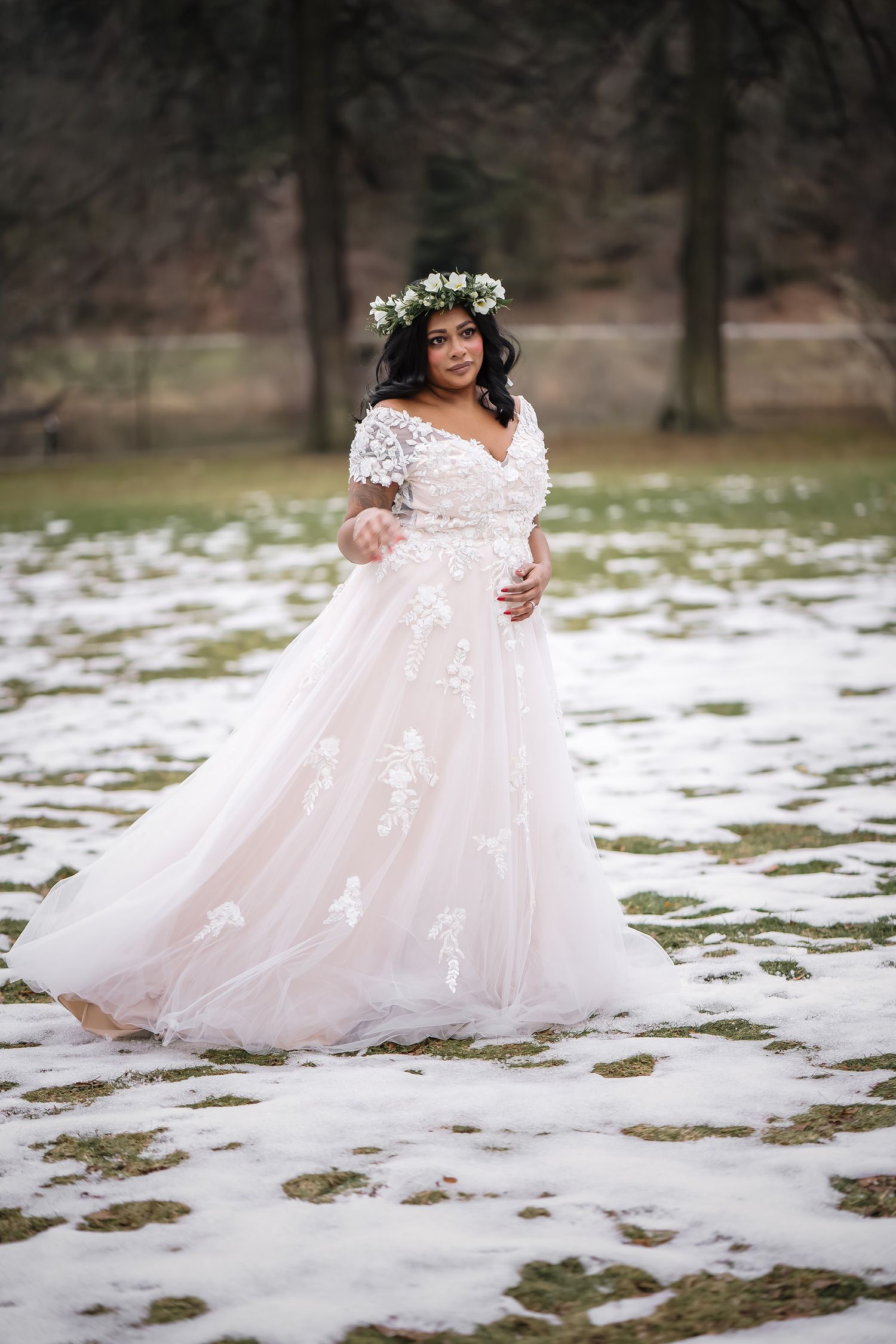 Ethereal bridal portrait in snow featuring lace gown and floral crown amid winter landscape.