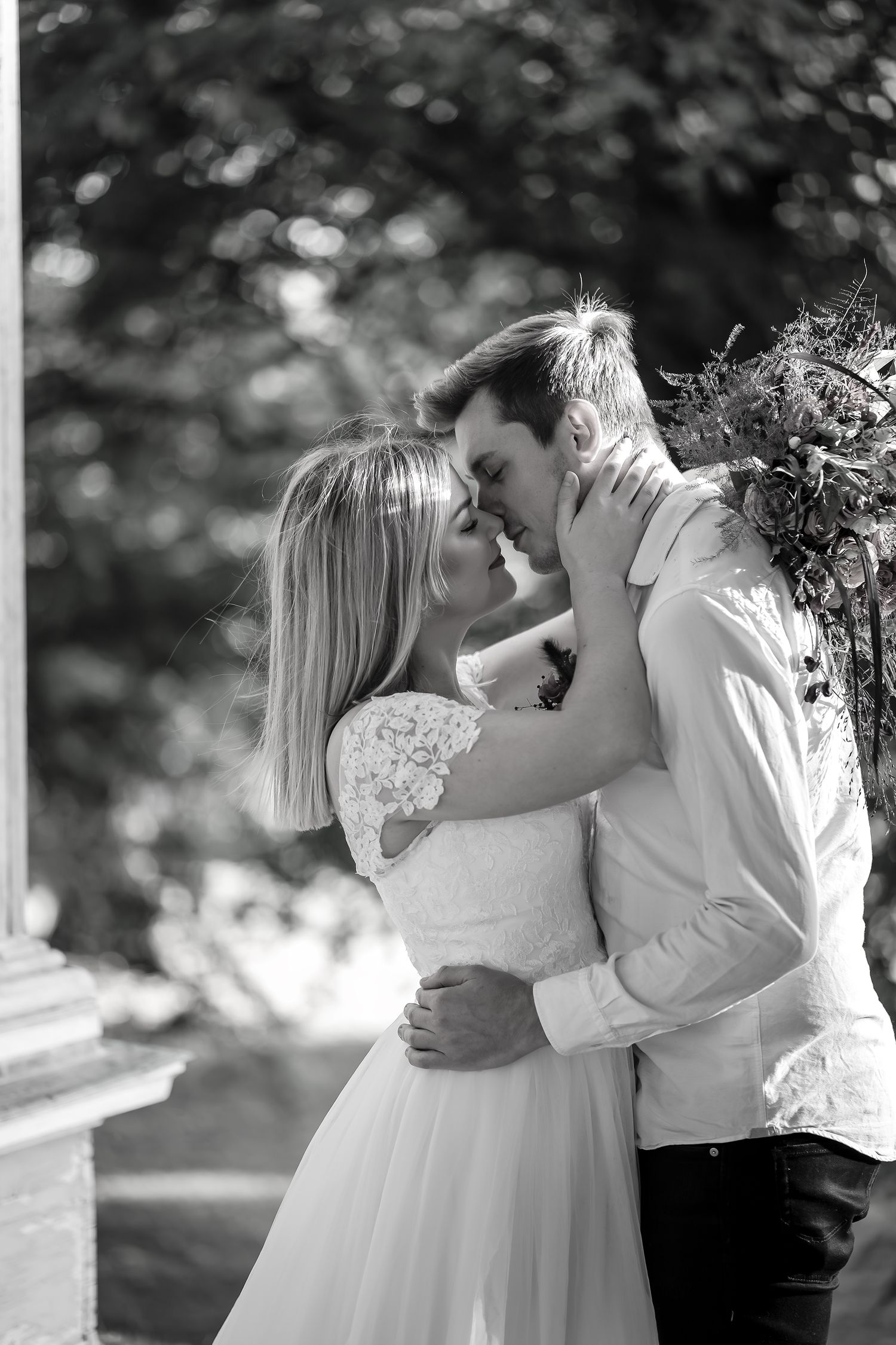 Intimate black and white portrait of newlyweds sharing tender moment outdoors.