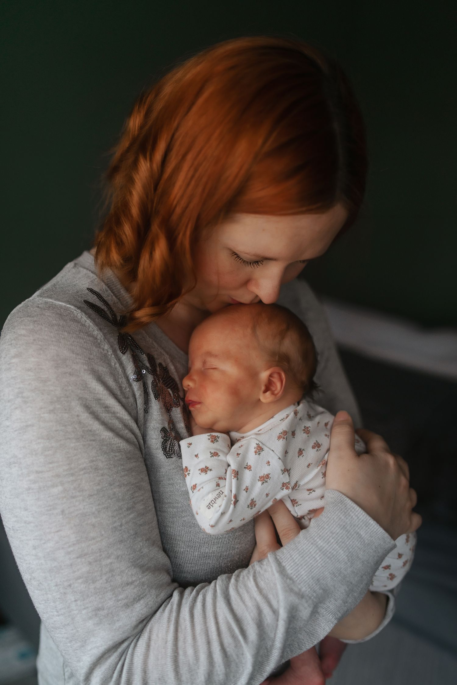 Tender moment captured between parent and newborn baby in soft lighting.