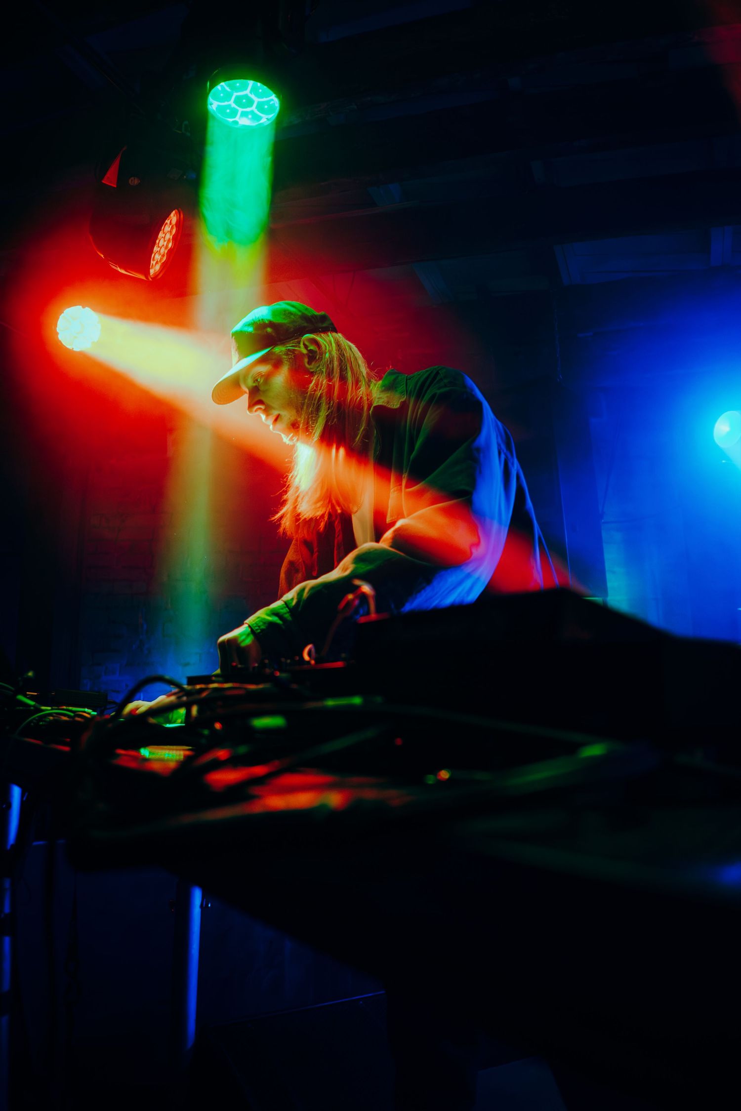 DJ performing at a nightclub with colorful red, green and blue lighting effects creating an atmospheric mood.