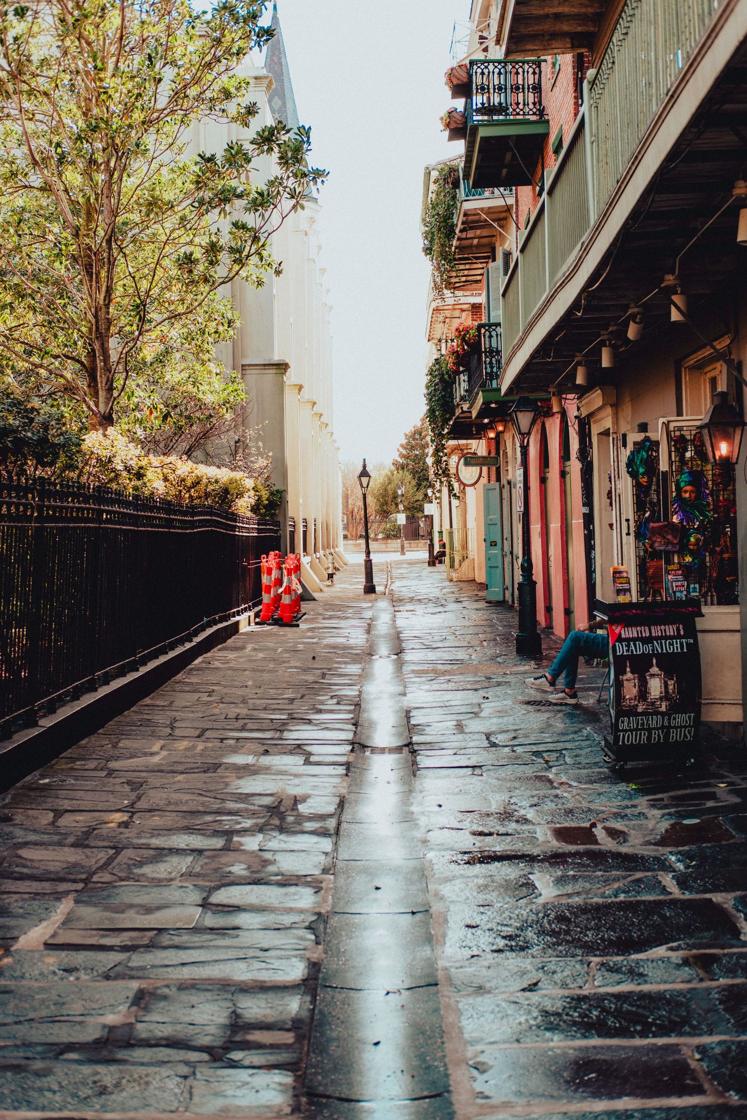 Wet cobblestone street lined with historic buildings in New Orleans' French Quarter.