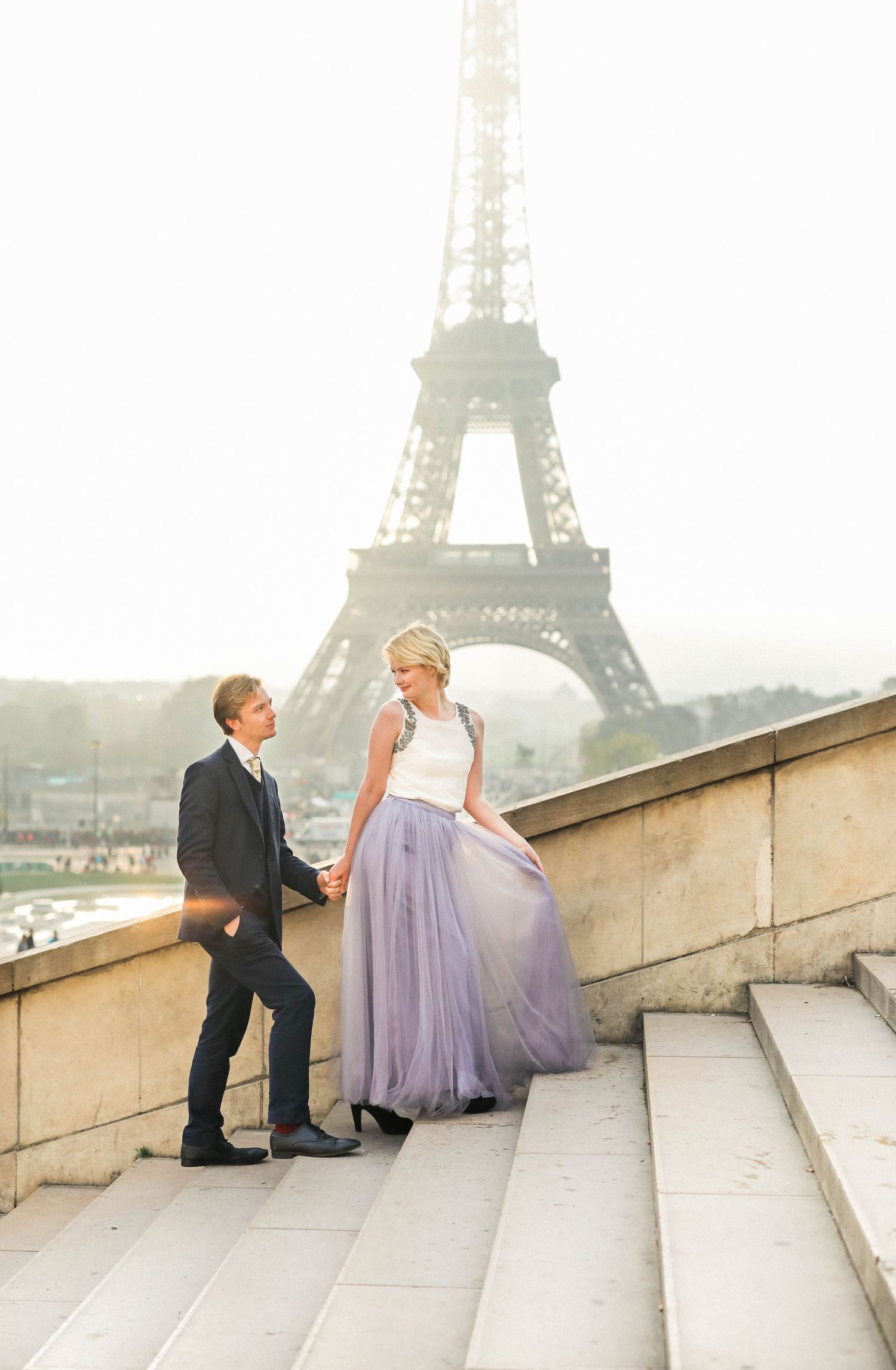 Couple posing in front of the Eiffel Tower in Paris in the sunrise for their engagement shoot