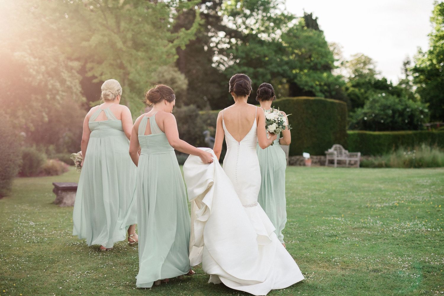 Bride and bridesmaids walking on lawn at elegant summer wedding Nettlestead Place Maidstone Kent