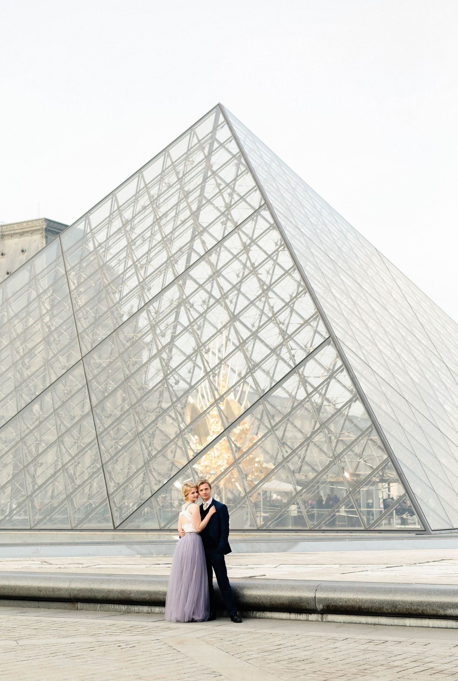 Couple posing in the Louvre in Paris in the sunrise for their engagement shoot
