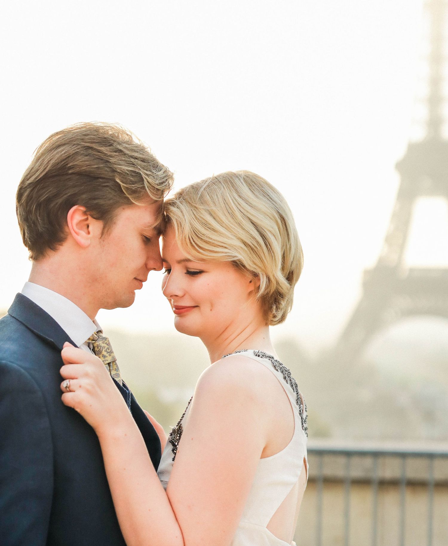 Couple posing in front of the Eiffel Tower in Paris in the sunrise for their engagement shoot