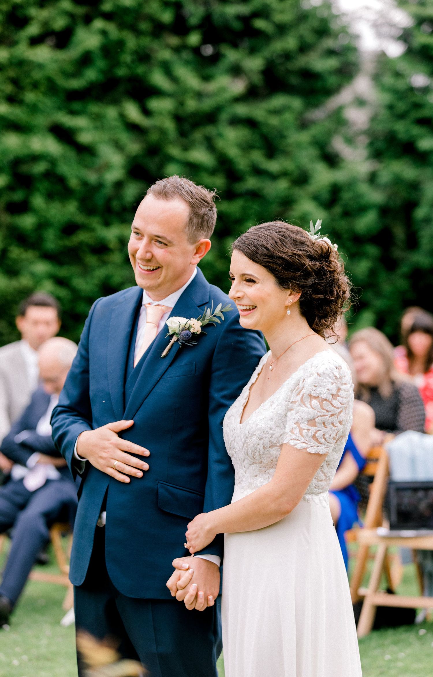 Happy wedding ceremony moment showing newlyweds laughing during officiant speech in London
