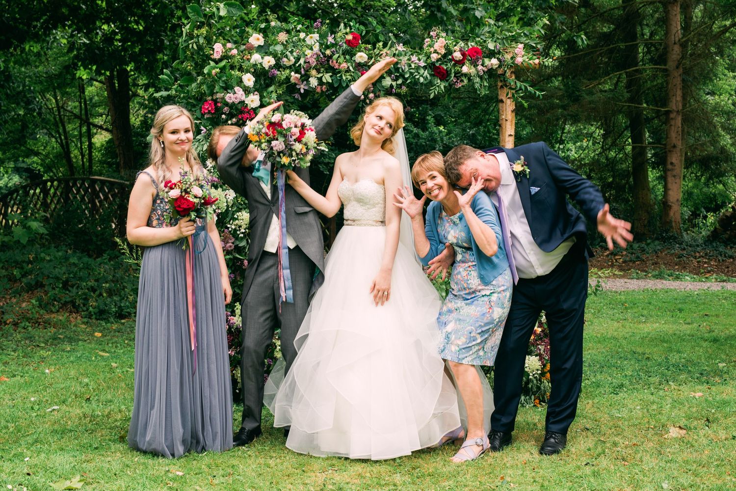 Playful silly poses of wedding group portrait of bride, groom and family members at reception venue