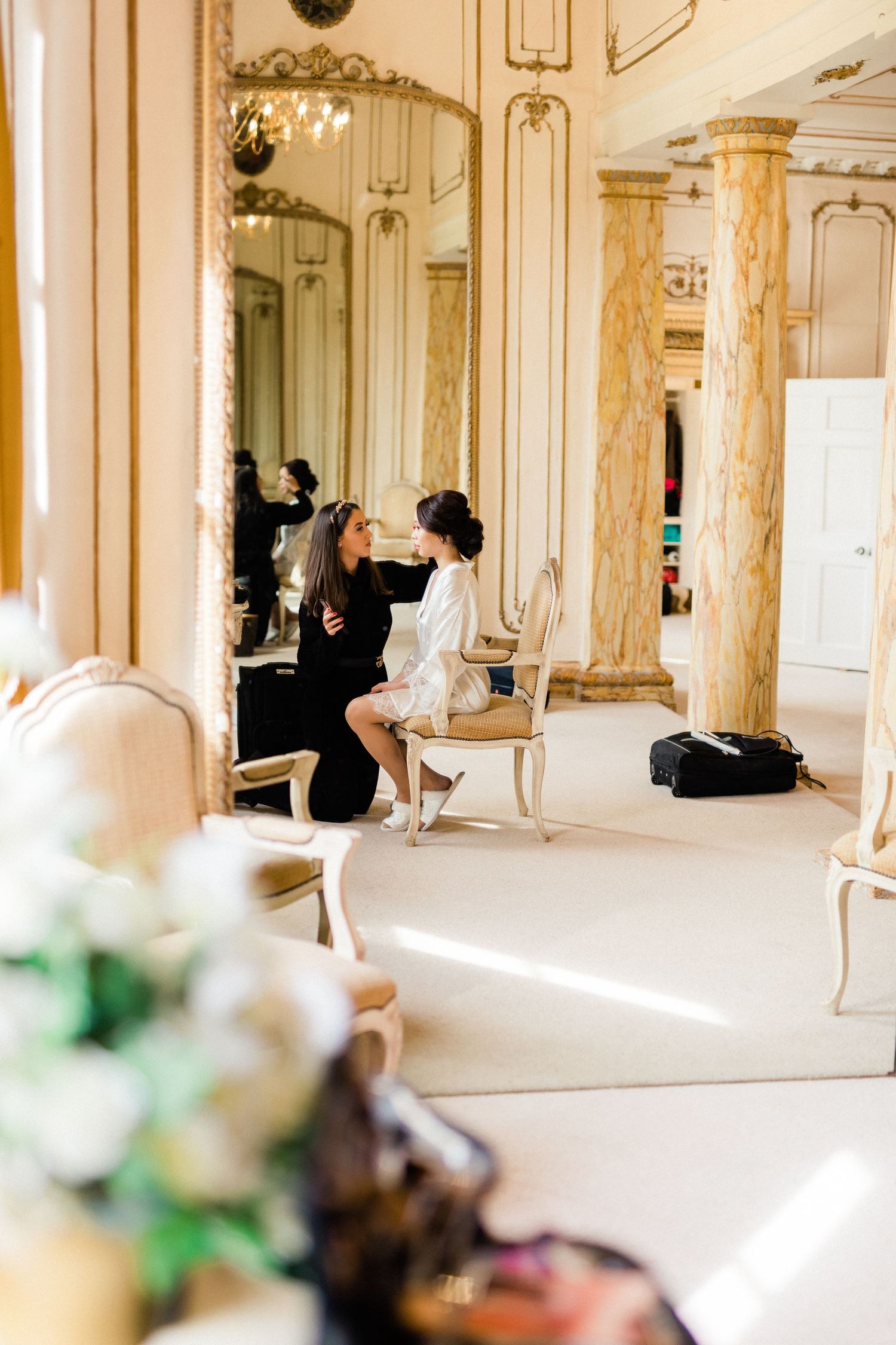 Candid moment of bride having makeup applied before wedding in Gosfield Hall essex