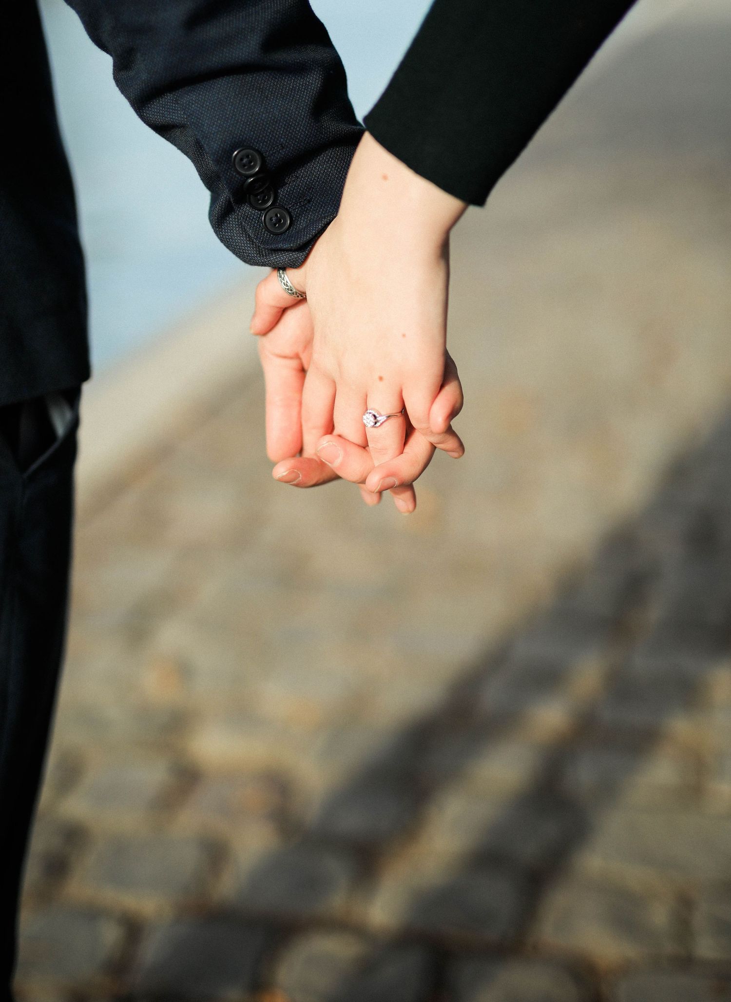 Detail shot of engagement ring whilst couple holding hands in an engagement shoot in Paris