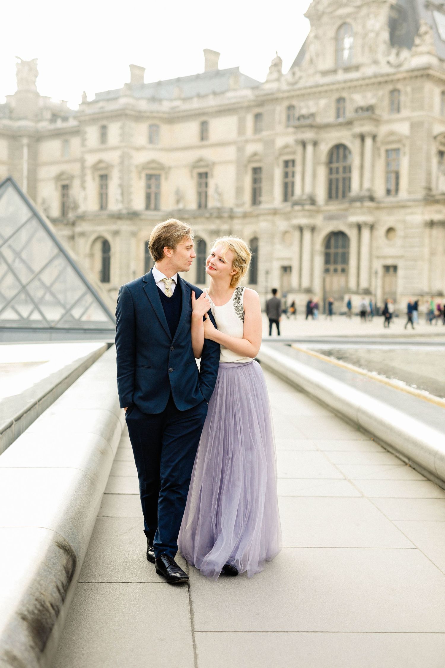 Couple posing in the Louvre in Paris in the sunrise for their engagement shoot