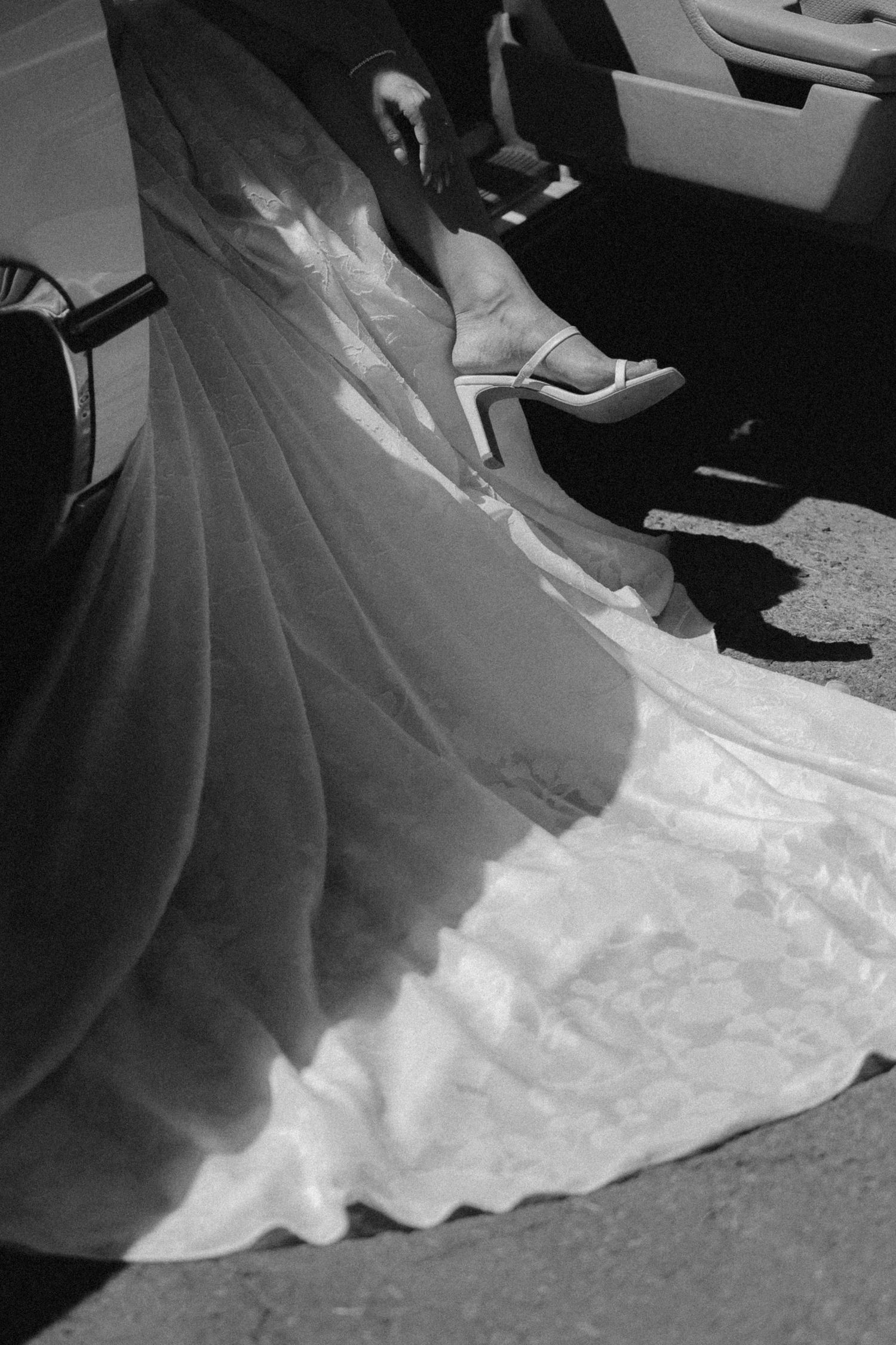 Detail shot of flowing white wedding dress train and bridal shoes in black and white.