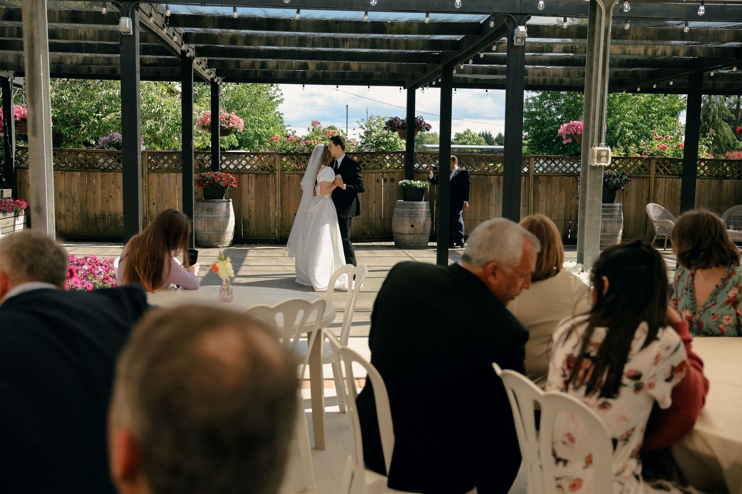 Guests gather under a covered outdoor venue during a wedding ceremony.