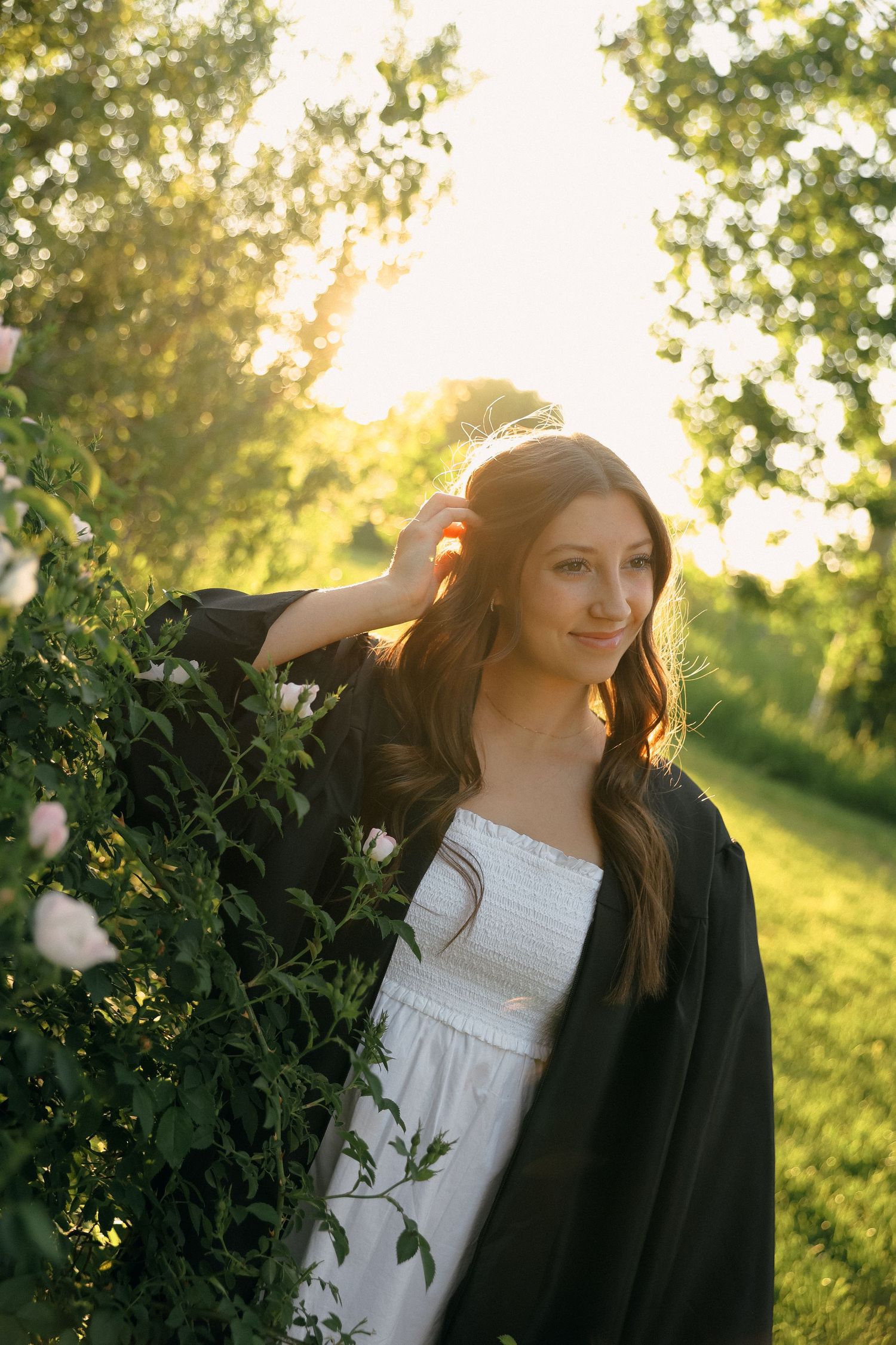 Graduation portraits in warm sunset lighting among lush green foliage.