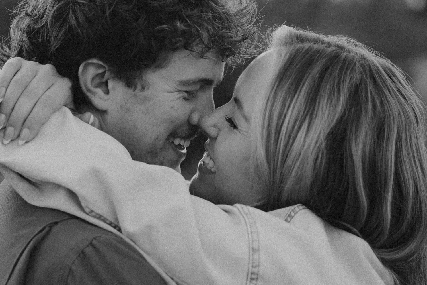 A close up black and white photograph shows an intimate moment between two people embracing and smiling.