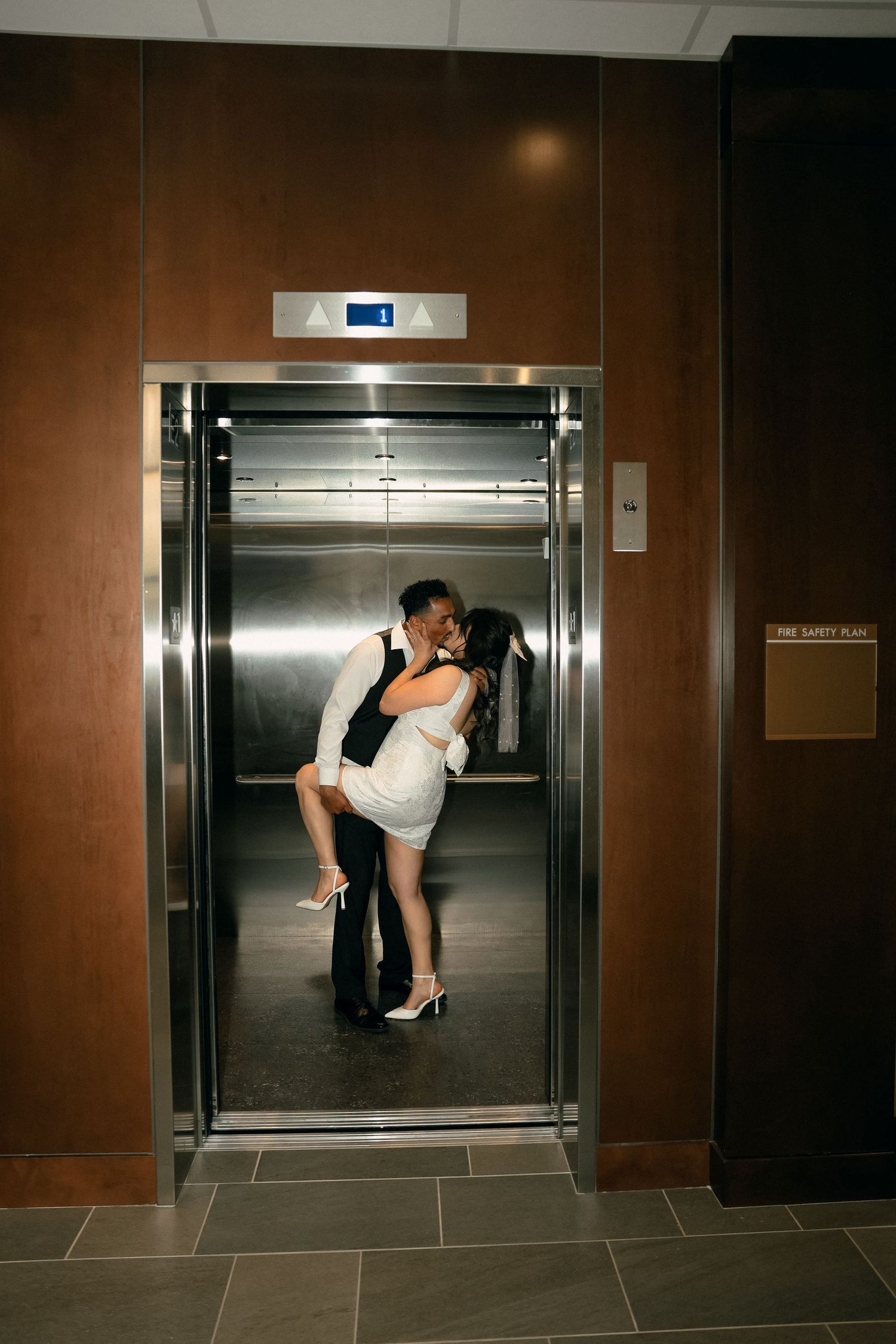 Romantic couple sharing an intimate moment in an elevator hallway.