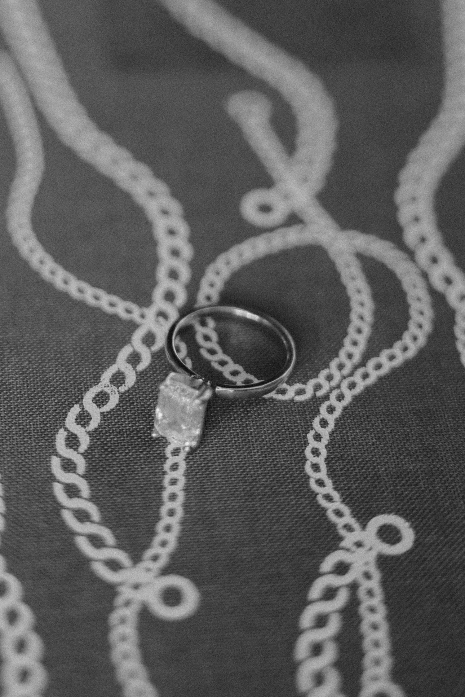 Close-up of delicate silver chain necklaces arranged in overlapping curves against a dark background.