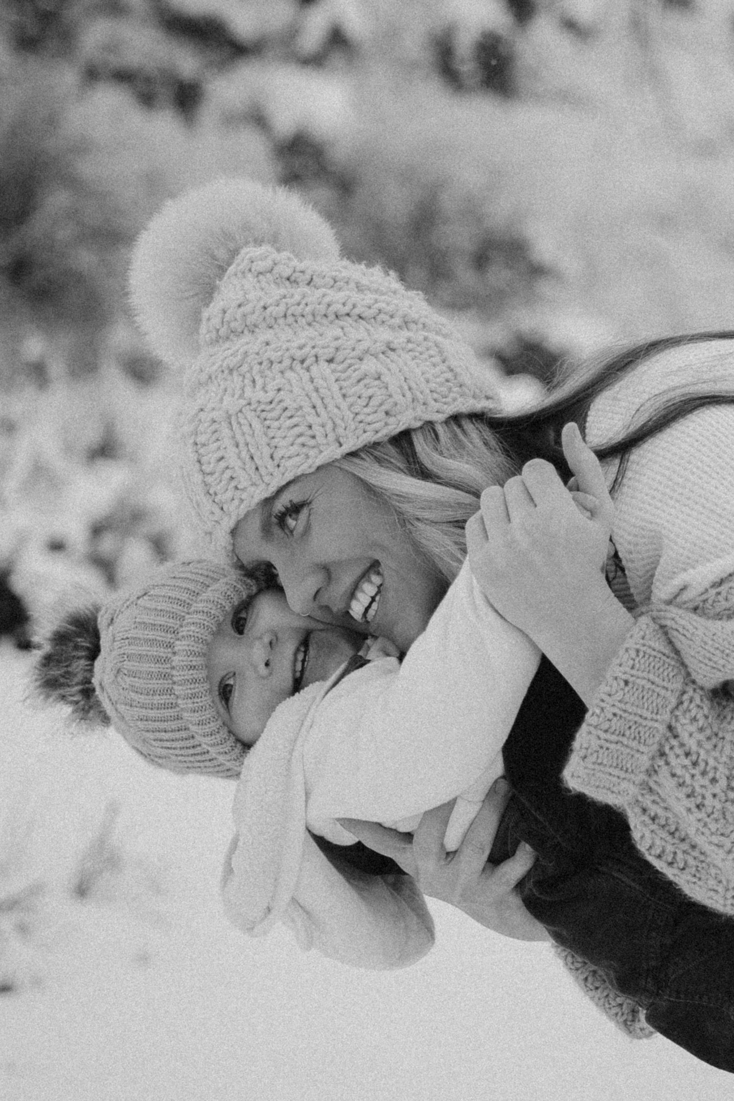 A heartwarming winter scene of two people in knit hats sharing a joyful embrace in the snow.