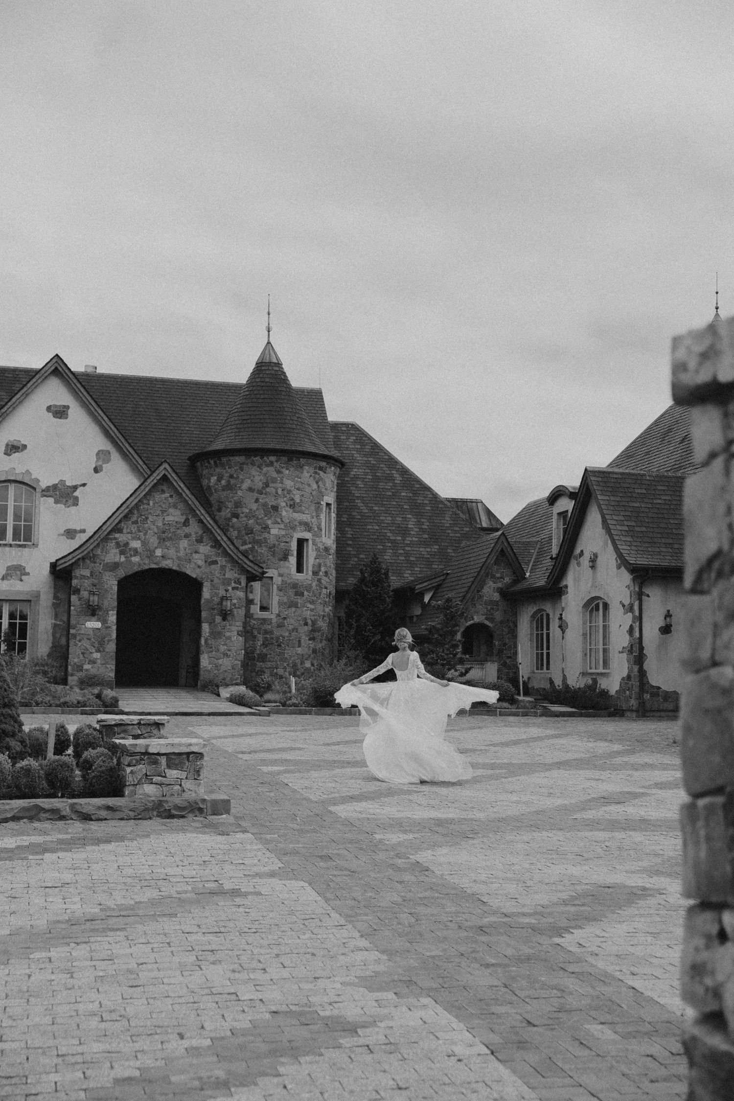 Black and white photo of stone buildings and courtyard at an upscale wedding venue.