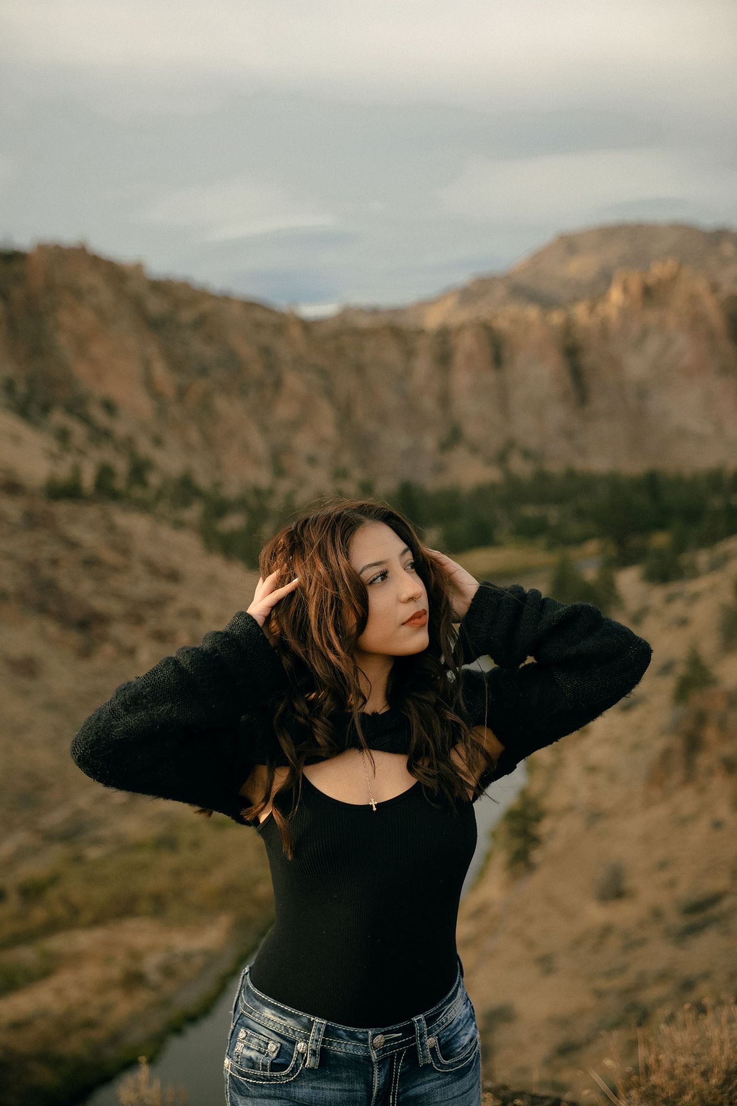 Fashion portrait against dramatic mountain backdrop with person in black top and denim.