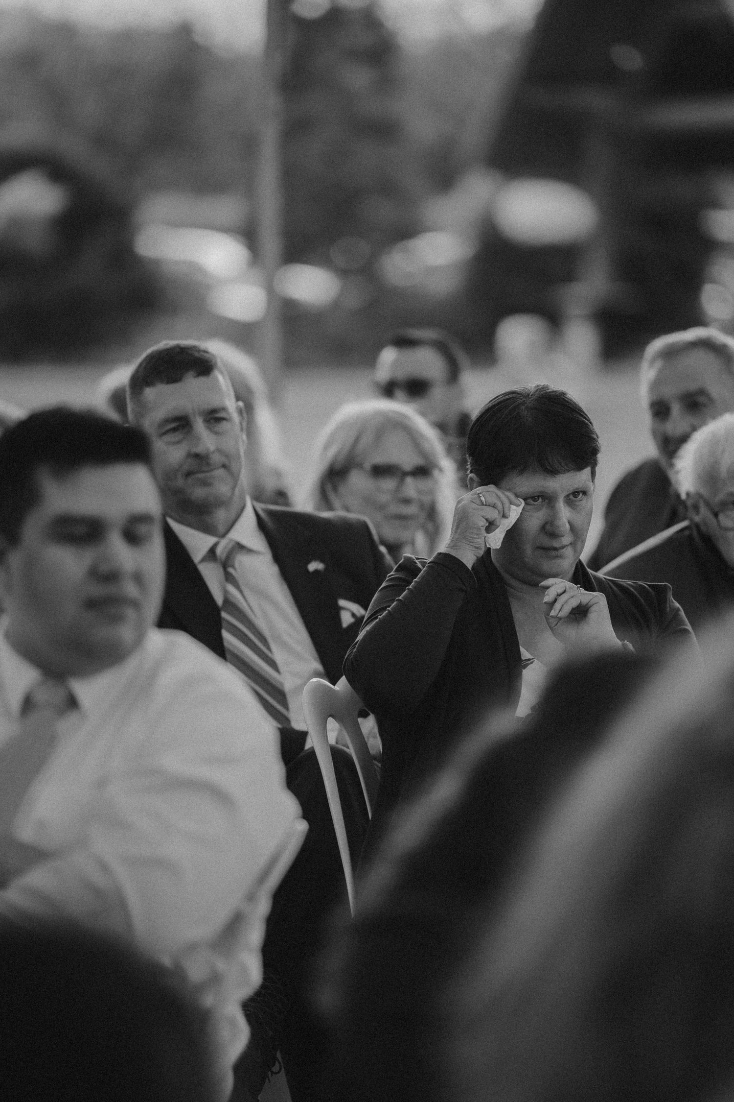 A crowd of wedding guests seated during an outdoor ceremony in black and white.