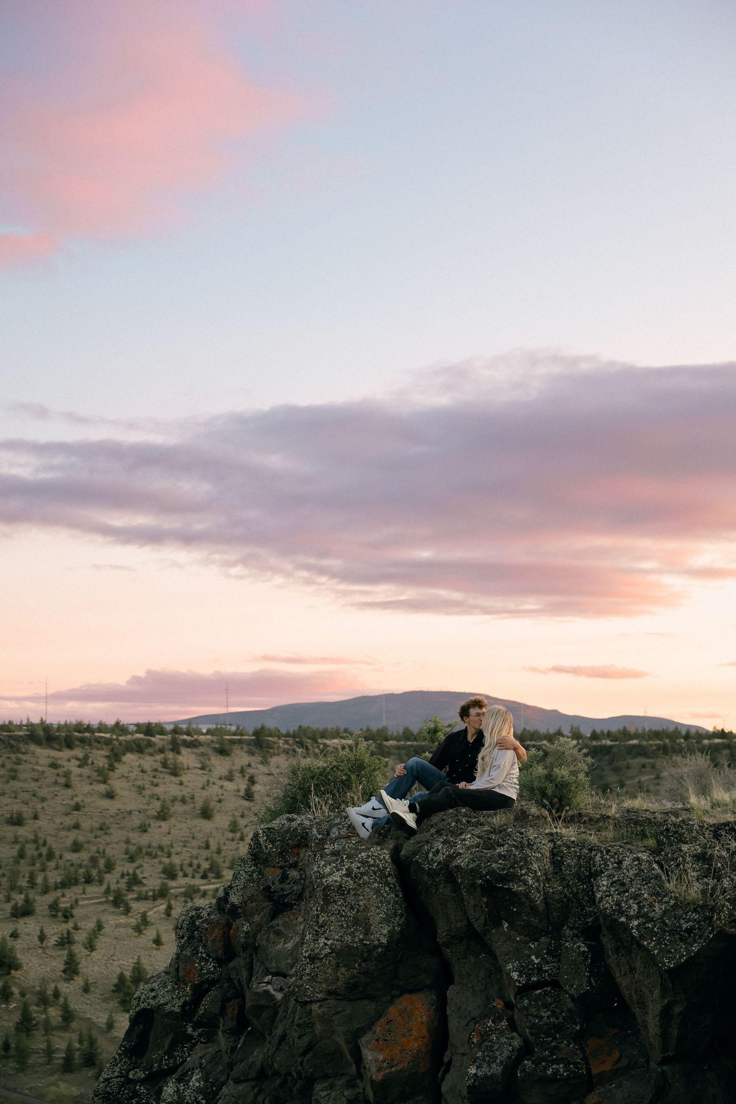 Panoramic sunset view over a rugged desert landscape with rocky cliffs and mountains.