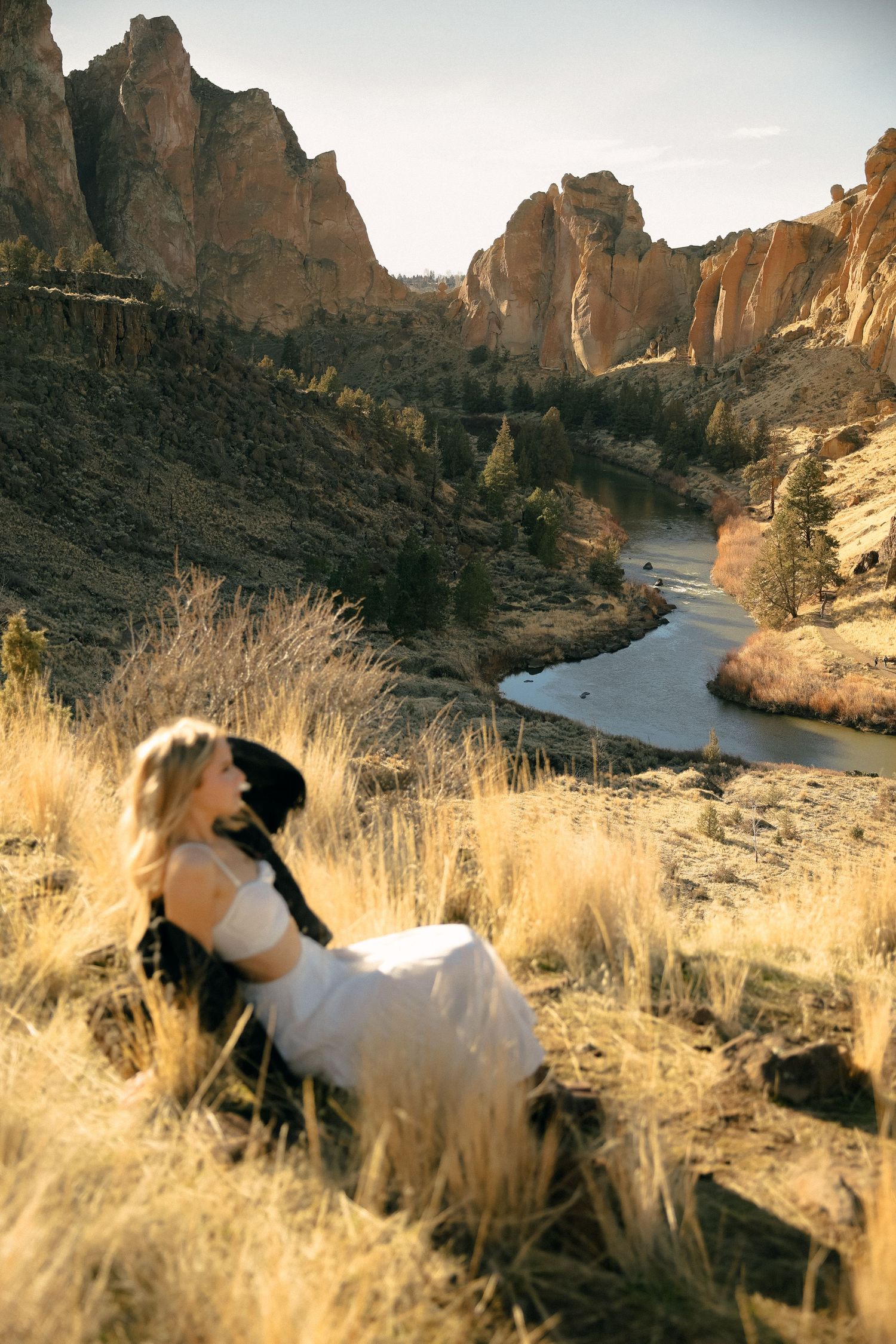Person in white dress overlooking dramatic Smith Rock State Park canyon and river.