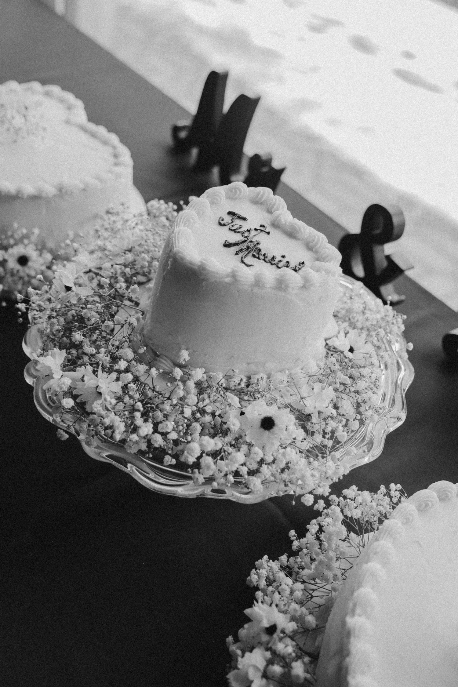 Elegant white wedding cake with delicate floral decorations photographed in black and white.