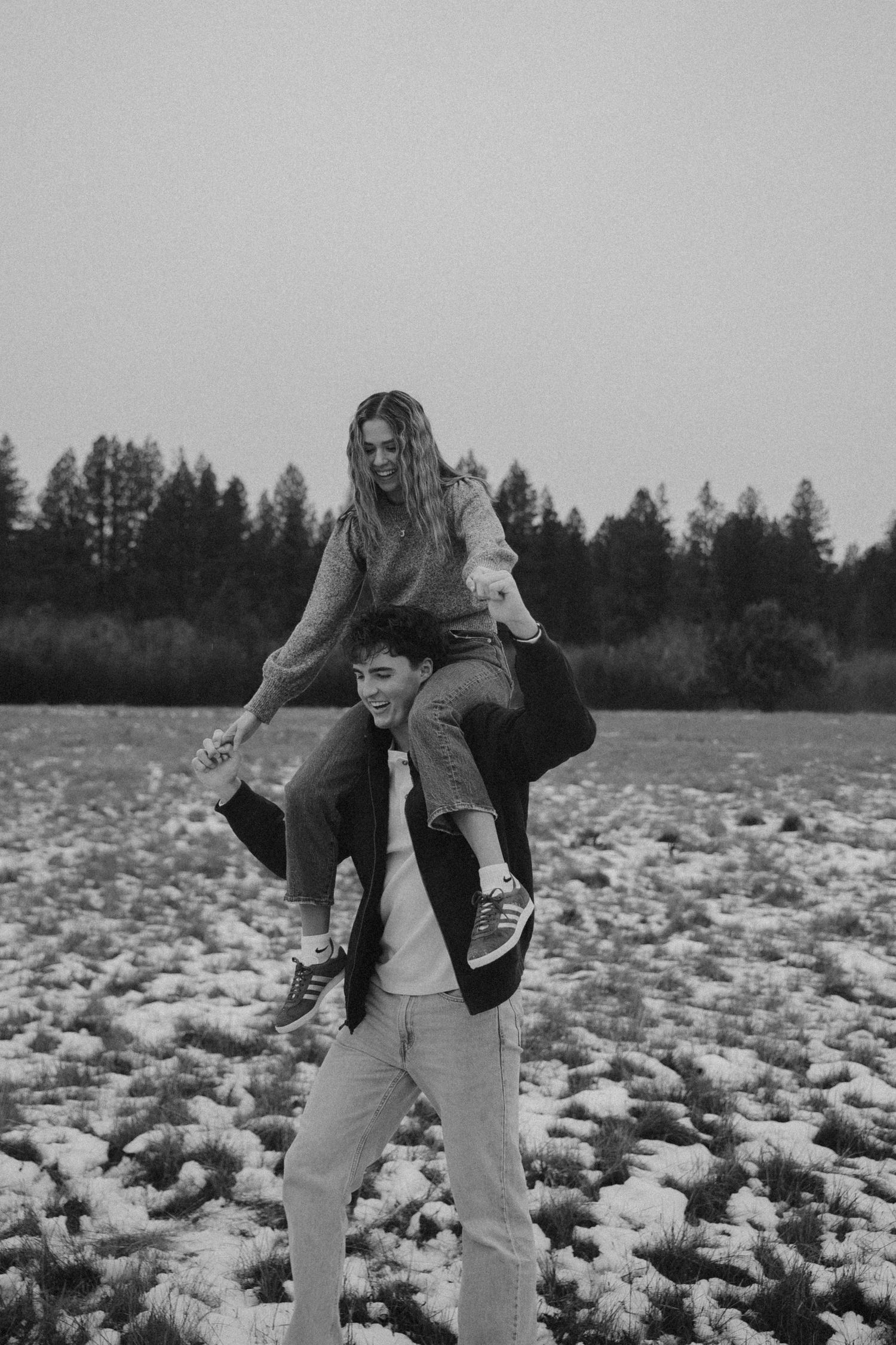 Person in casual clothing dancing playfully in a snowy winter field.