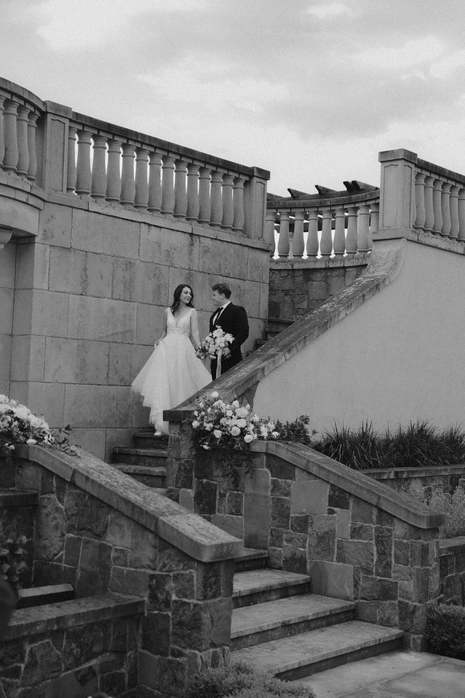 Wedding couple descending stone steps in dramatic black and white photography.