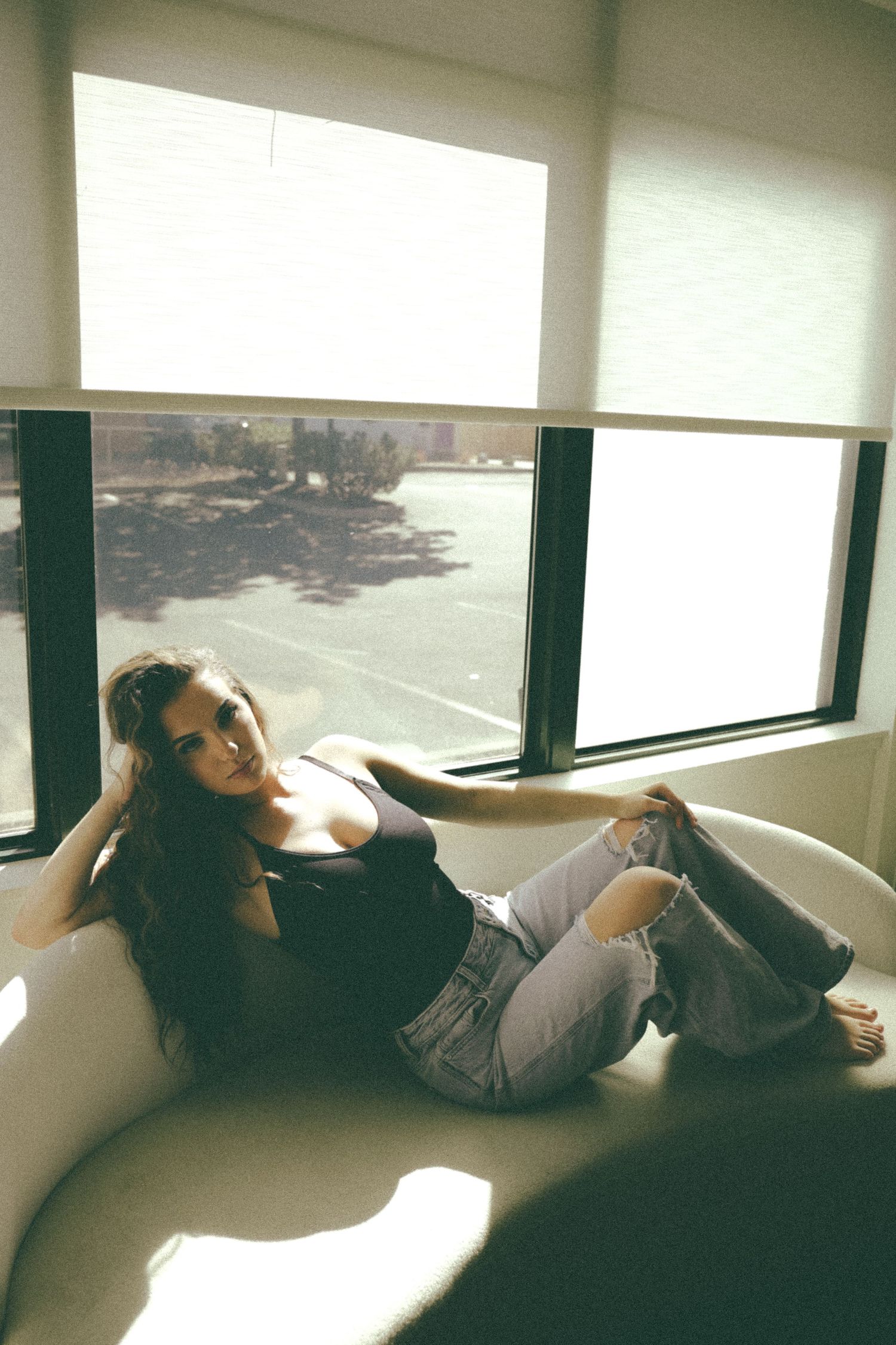 Artistic portrait of person relaxing on window seat with dramatic natural lighting.