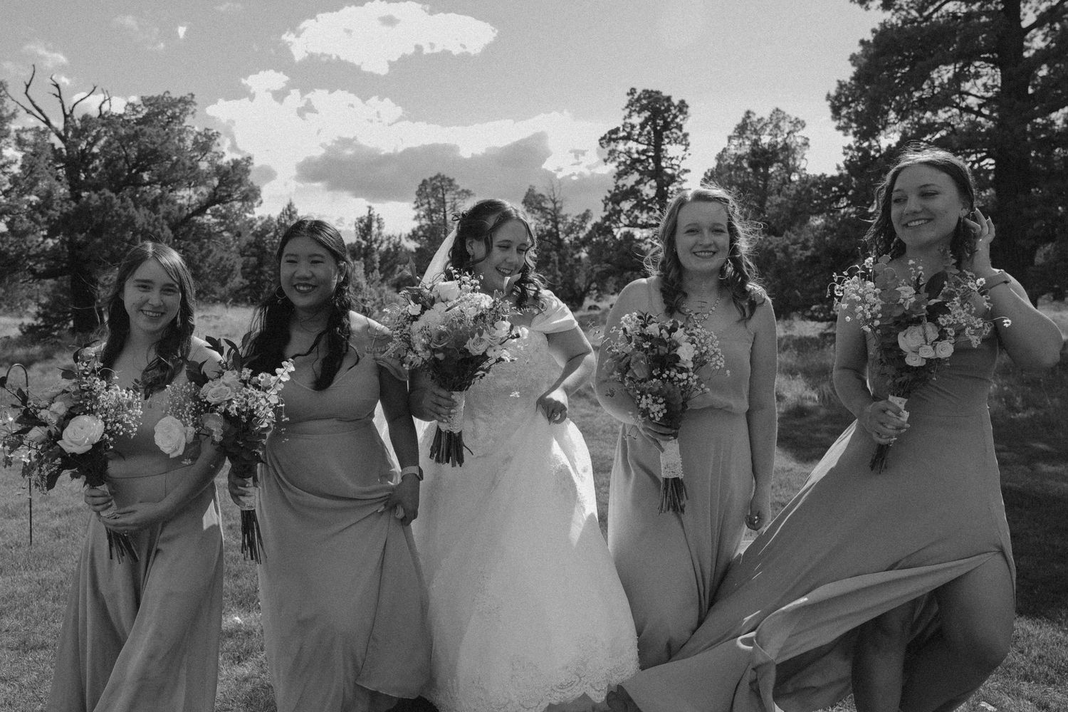 Bridesmaids holding bouquets pose together in black and white photo.