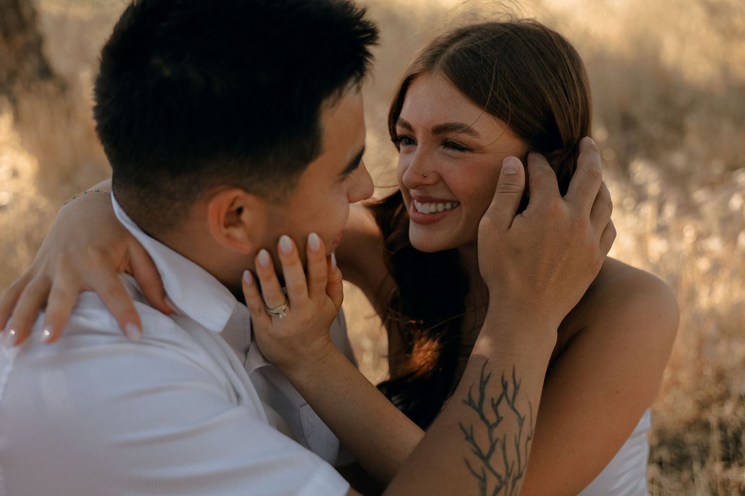Couple shares an intimate moment in a sunlit field during golden hour.