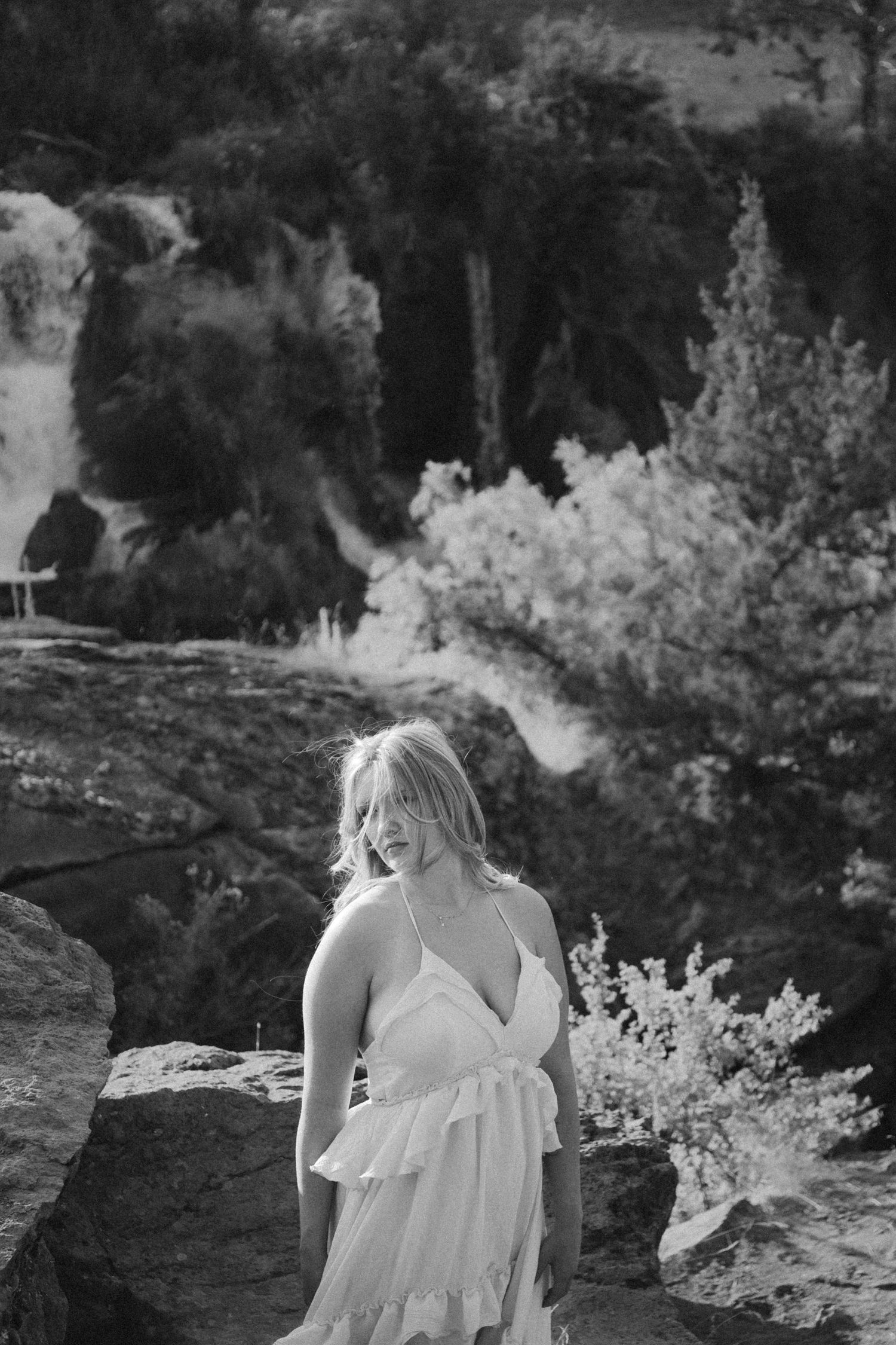 Black and white portrait of a person in white dress amid natural outdoor setting.