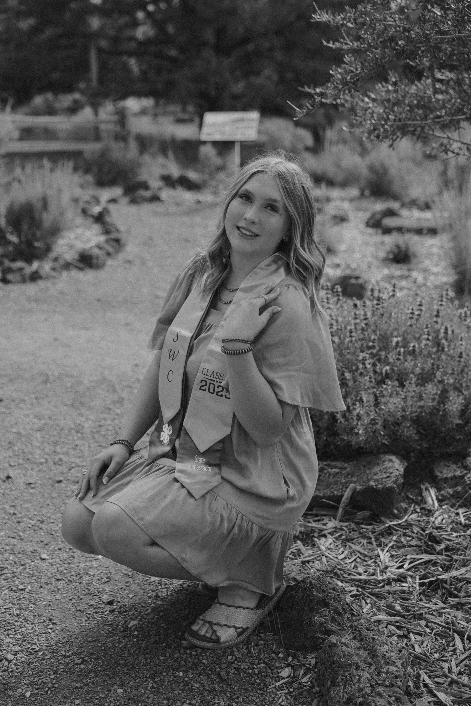Black and white portrait taken among desert wildflowers and rocky terrain.
