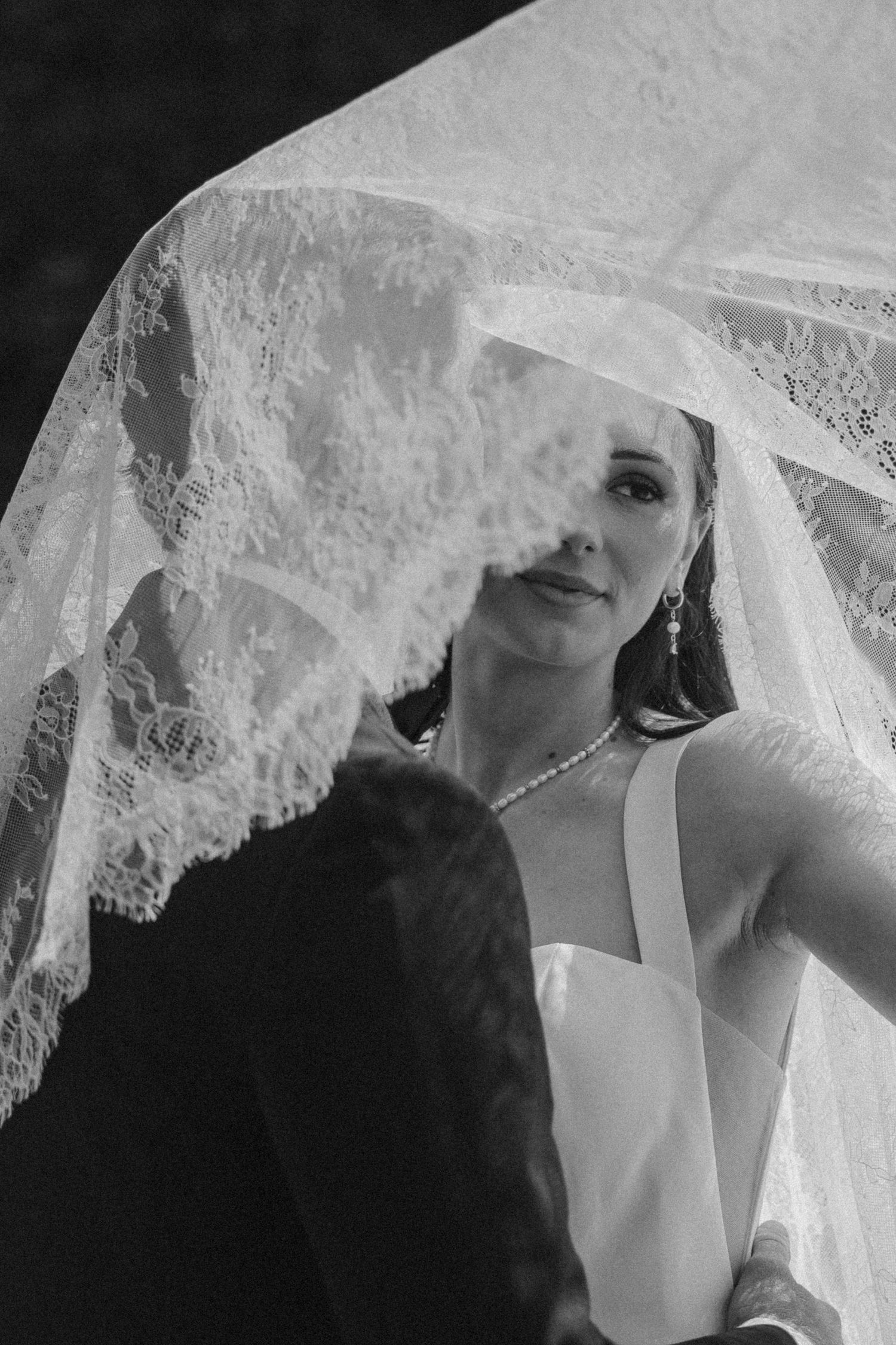 A series of intimate black and white wedding photographs showing the couple through delicate lace veil details.
