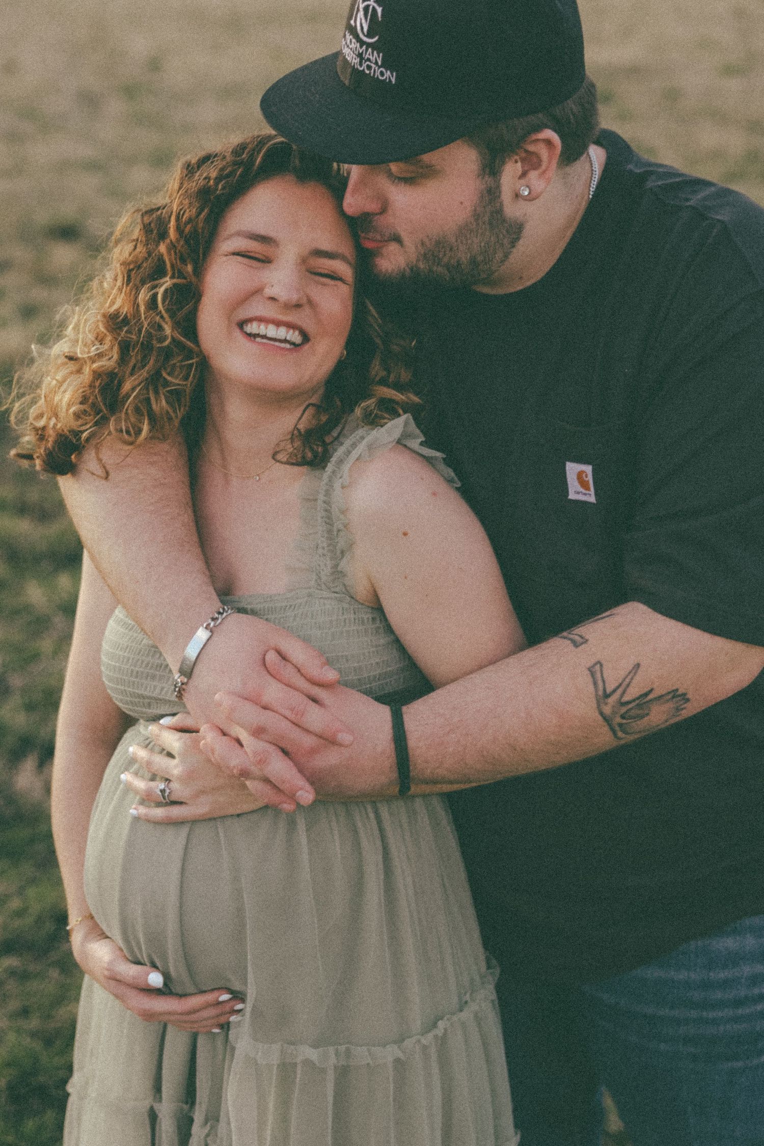 A couple shares an intimate embrace while laughing in golden sunlight.