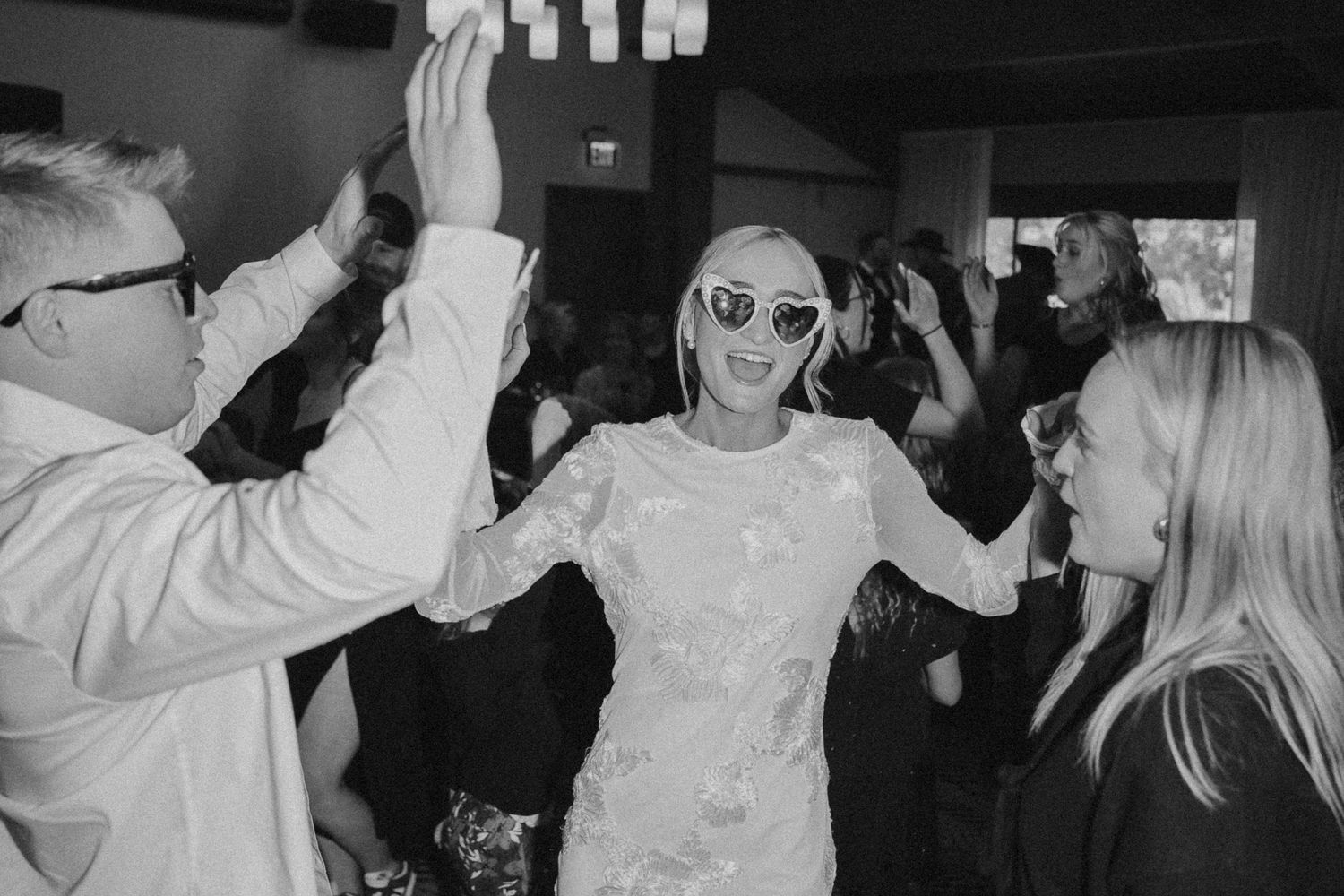 Joyful wedding reception scene with guests dancing and celebrating in black and white.