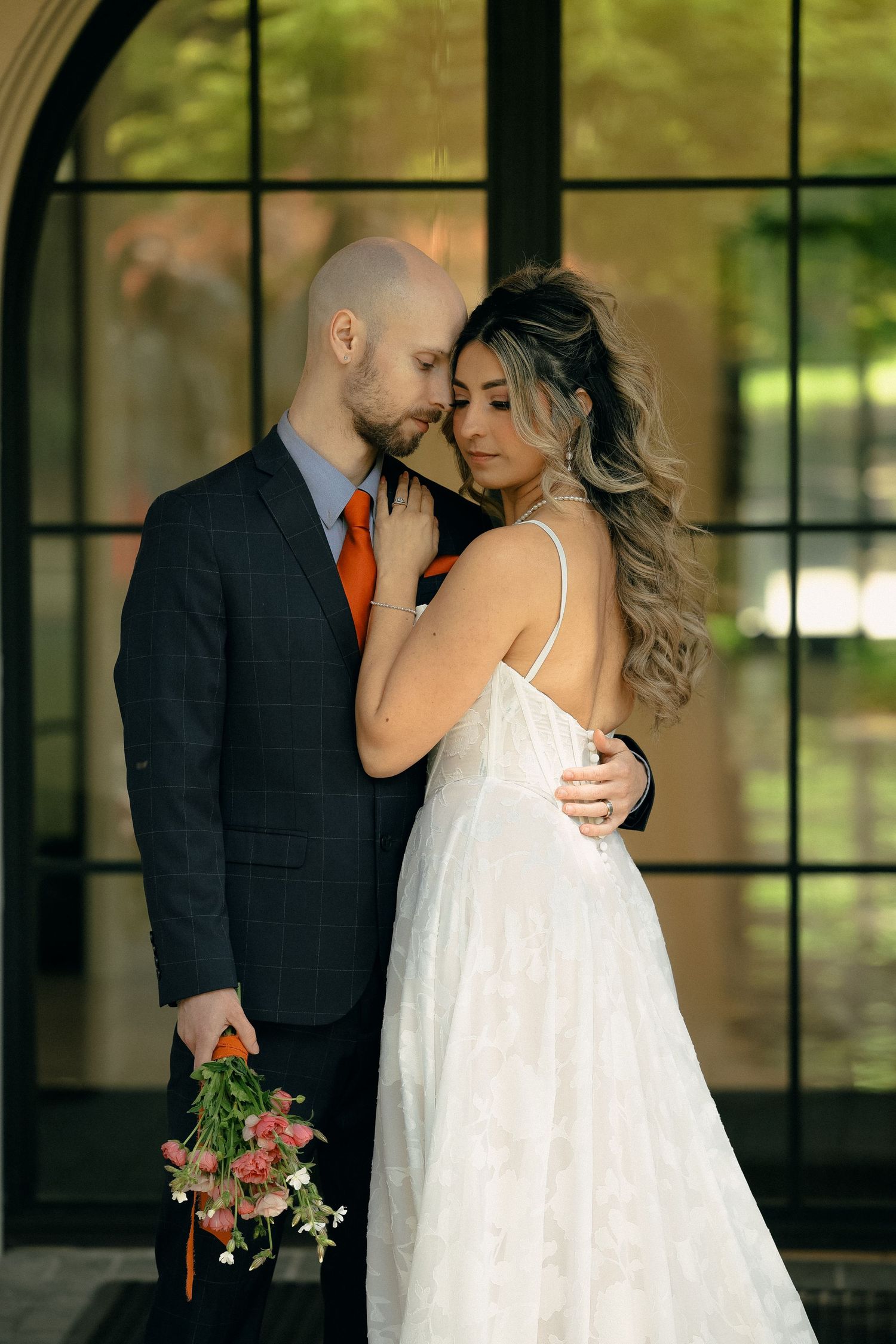 Intimate moment between newlyweds against black window frames.