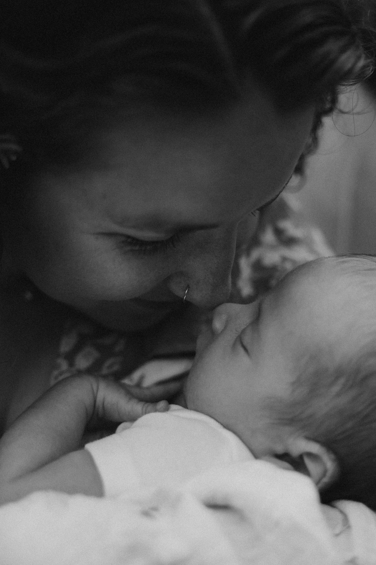 A tender moment captured in black and white as parent and baby share a close embrace.