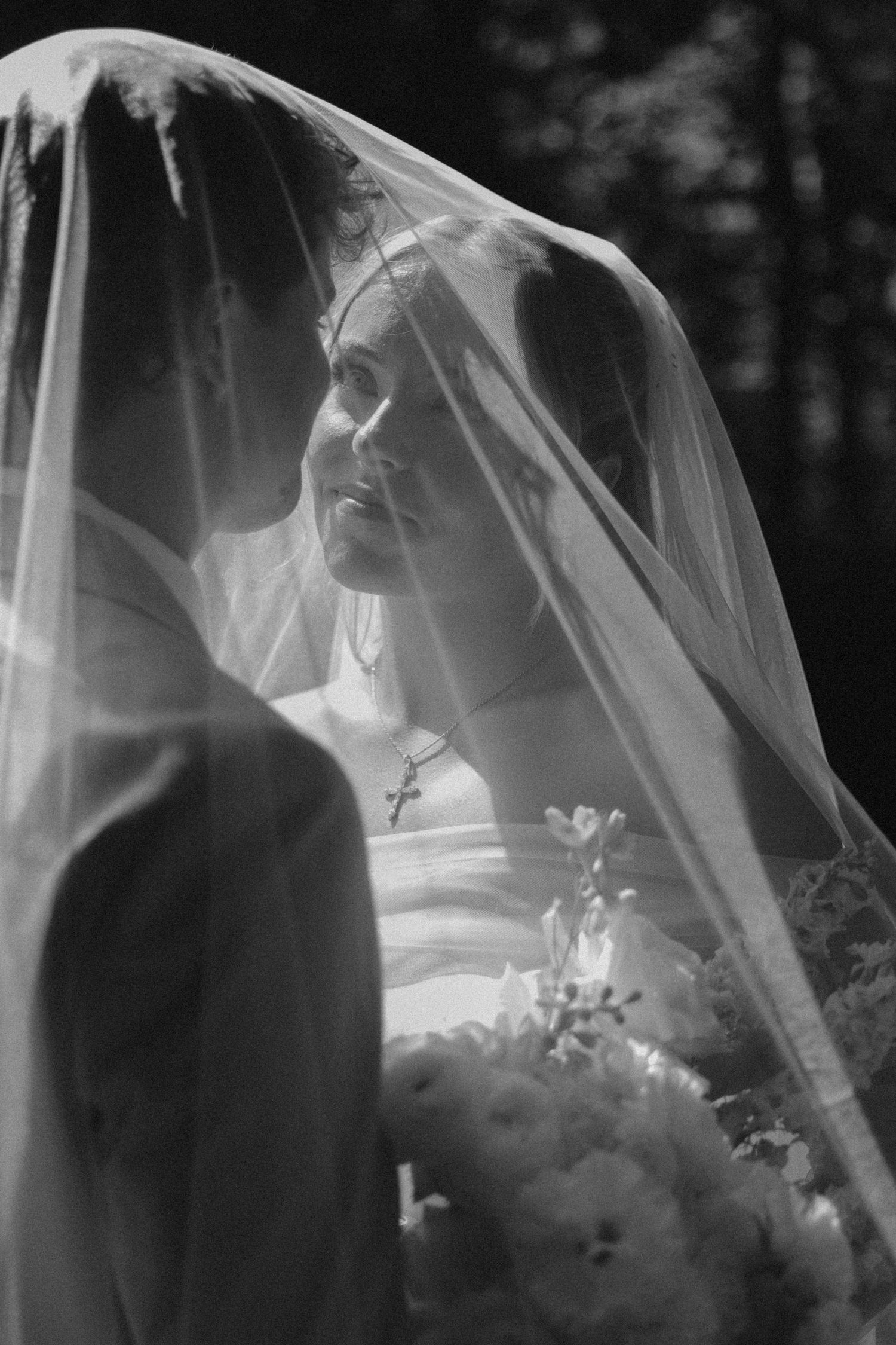 Close-up shots of a bride wearing a delicate veil in a black and white outdoor wedding photo series.